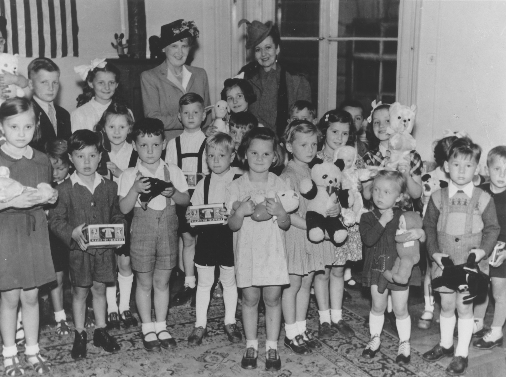 Group portrait of Jewish orphans who had survived Theresienstadt with the wife of Czech President Edvard Benes and the wife of the American Ambassador Laurence Steinhart.  Each child holds a newly received toy.

Among those pictured is Judis Baehr.