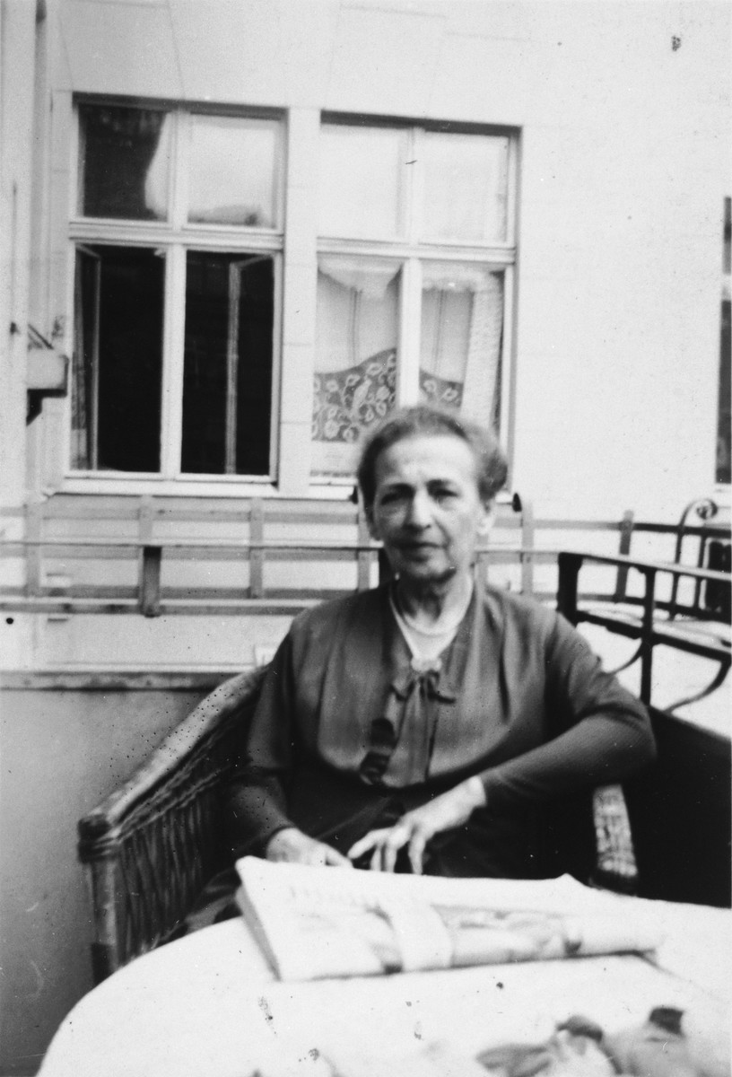 A German-Jewish woman sits on a porch on a wicker chair with her newspaper.

Pictured is Olga Cohn, grandmother of the donor.