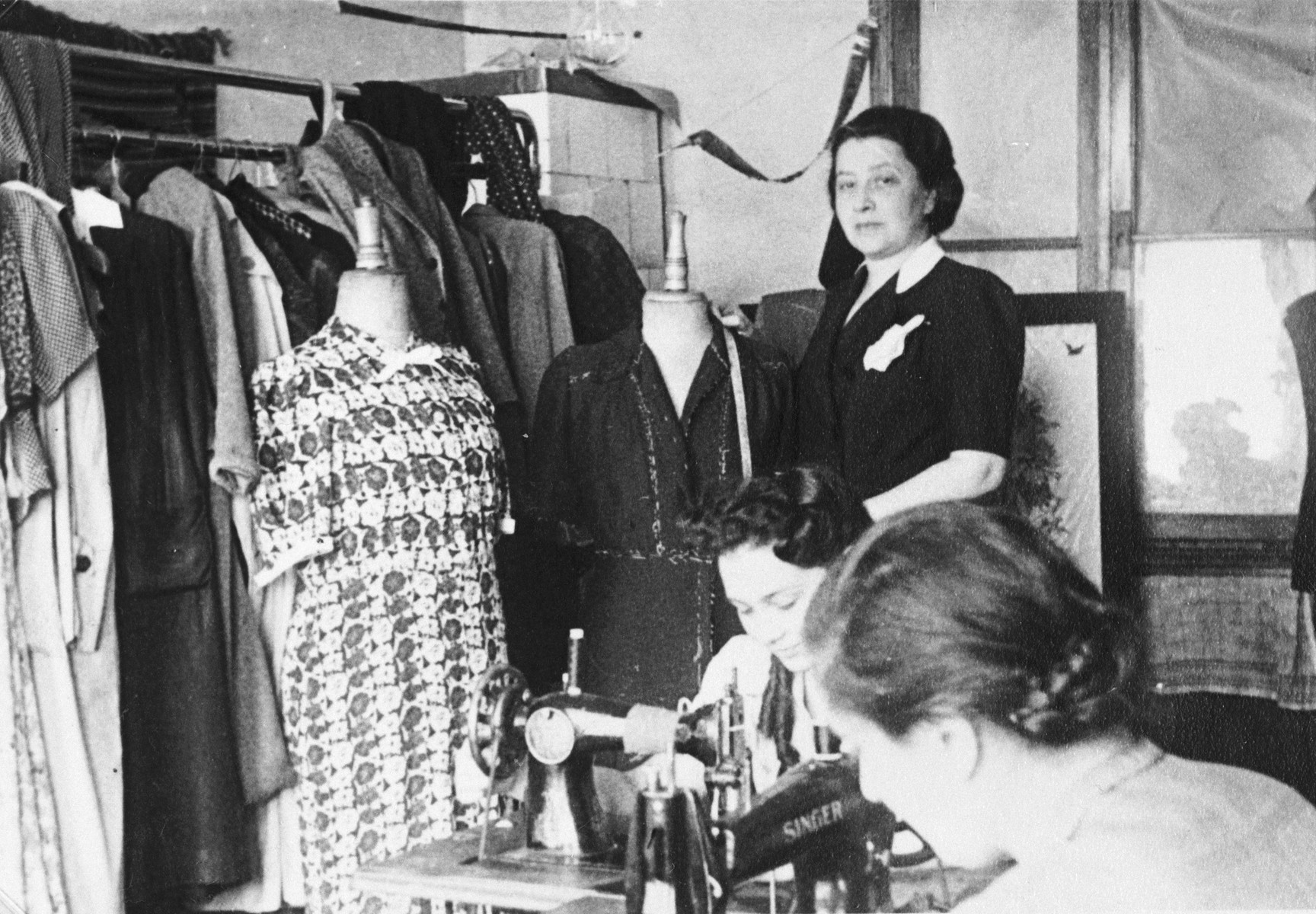 Female employees work in the Julius Madritsch Ladies' Custom Shop.

Standing is the manager Mrs. Minder and seated at the machine is Dziunia Eichenholz.