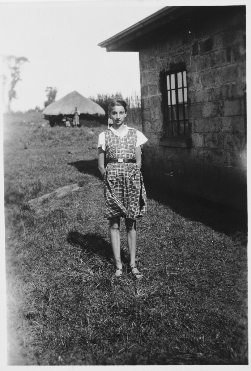 A Jewish refugee child poses outside her family's farmhouse near Limuru, Kenya (Kiambu district), where they found refuge during World War II.

Pictured is Inge Berg.  A thatched roof shelter can be seen in the distance.