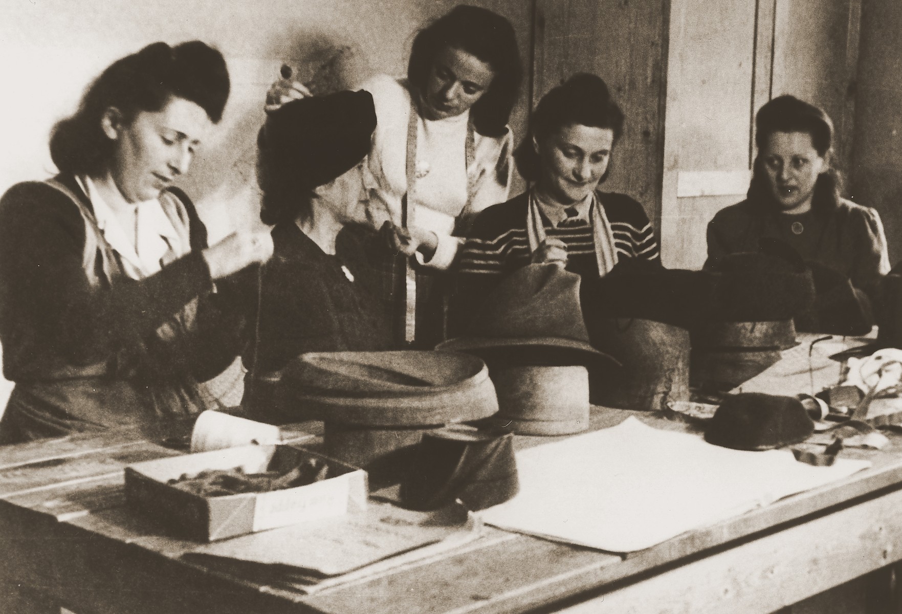 M. Kempner instructs four women in the trade of hat making at the ORT vocational training school in the Stuttgart DP camp.

One image from the Stuttgart Jewish DP camp album entitled, "Jidiszer D.P. Center UNRRA--P.C.IRO in Stuttgart," compiled and photographed by Alexander Fiedel and dedicated to Moses Kornberg, head of the commissary.