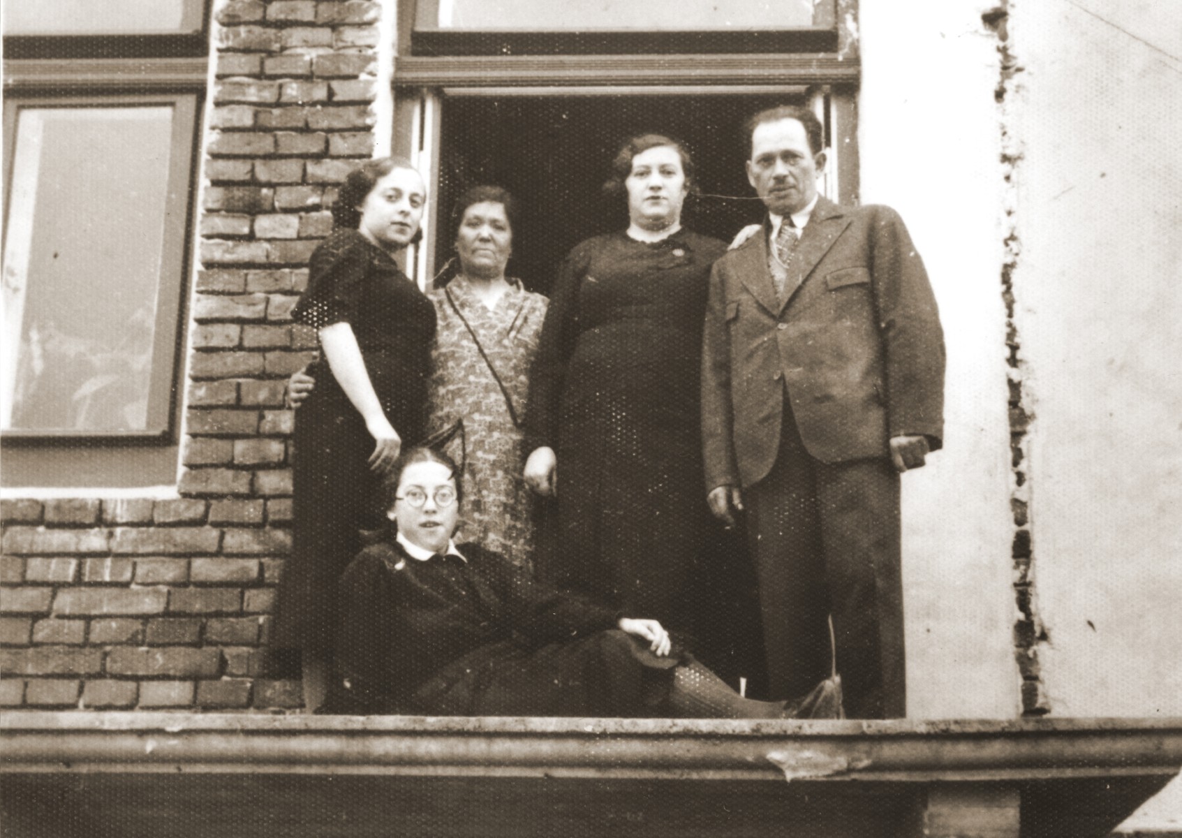 Members of the Berland family on the unfinished balcony of their home in Chelm.

Pictured standing from left to right are: Hela Zonenszein; Chaya Rachel Hilf; Sara Berland and Abraham Berland.  Felicja Berland lies in front of them.