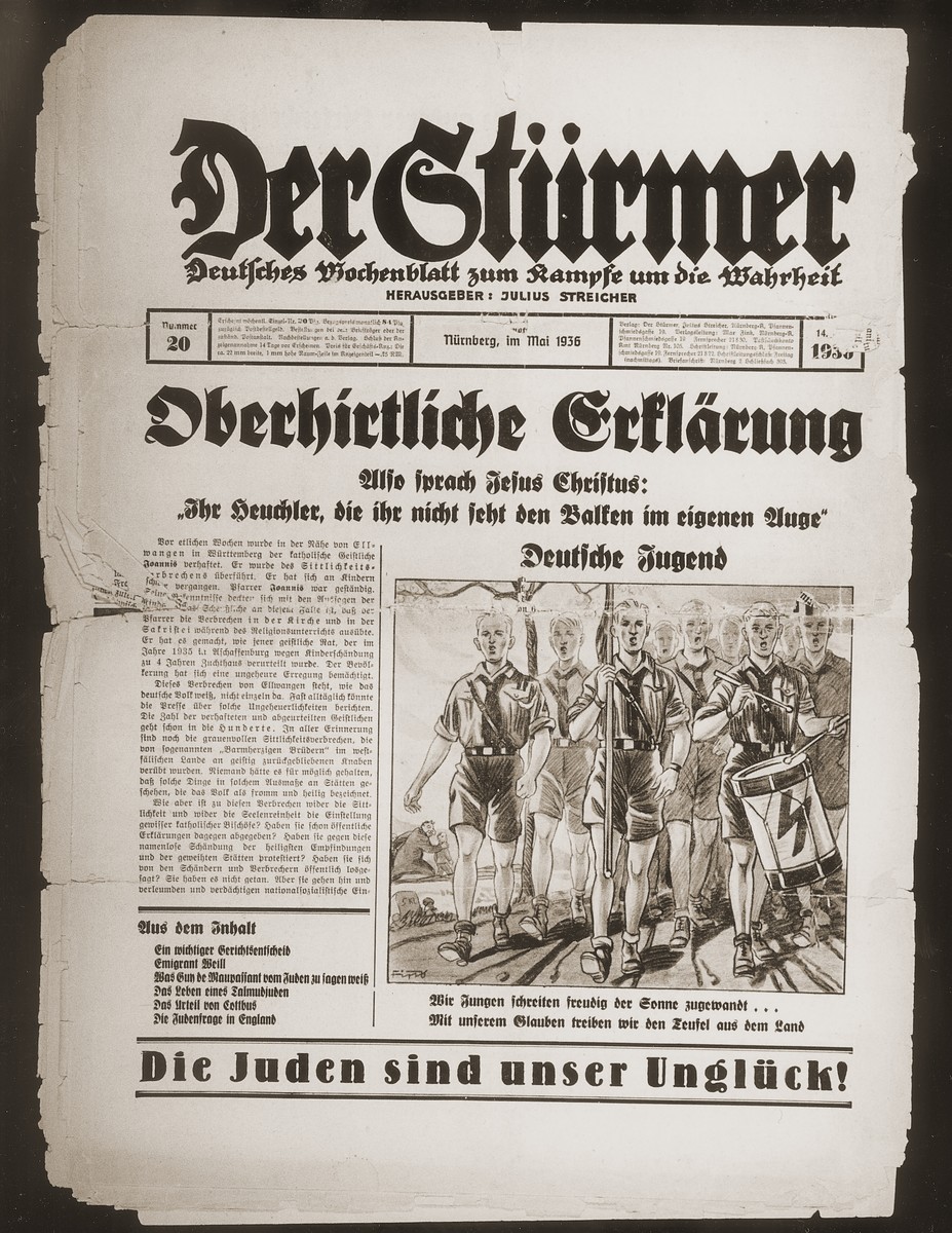 Front page of the Nazi publication, Der Stuermer, with a cartoon depicting a group of Hitler Youth marching forth to drive the forces of evil from the land.  The caption under the cartoon reads, "We youth step happily forward facing the sun... With our faith we drive the devil from the land."

The headline reads, "Declaration of the Higher Clergy/So spoke Jesus Christ: You hippocrites who do not see the beam in your own eyes.