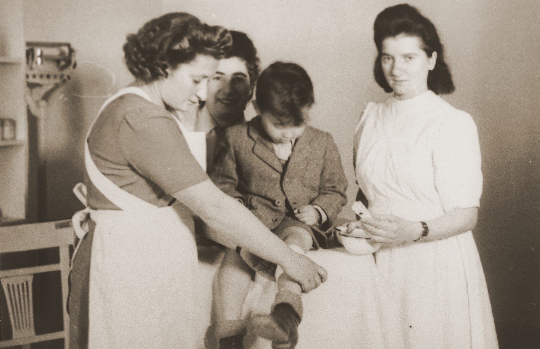 Nurses bandage the leg of a young boy at the clinic in the Stuttgart DP camp.

One image from the Stuttgart Jewish DP camp album entitled, "Jidiszer D.P. Center UNRRA--P.C.IRO in Stuttgart," compiled and photographed by Alexander Fiedel and dedicated to Moses Kornberg, head of the commissary.