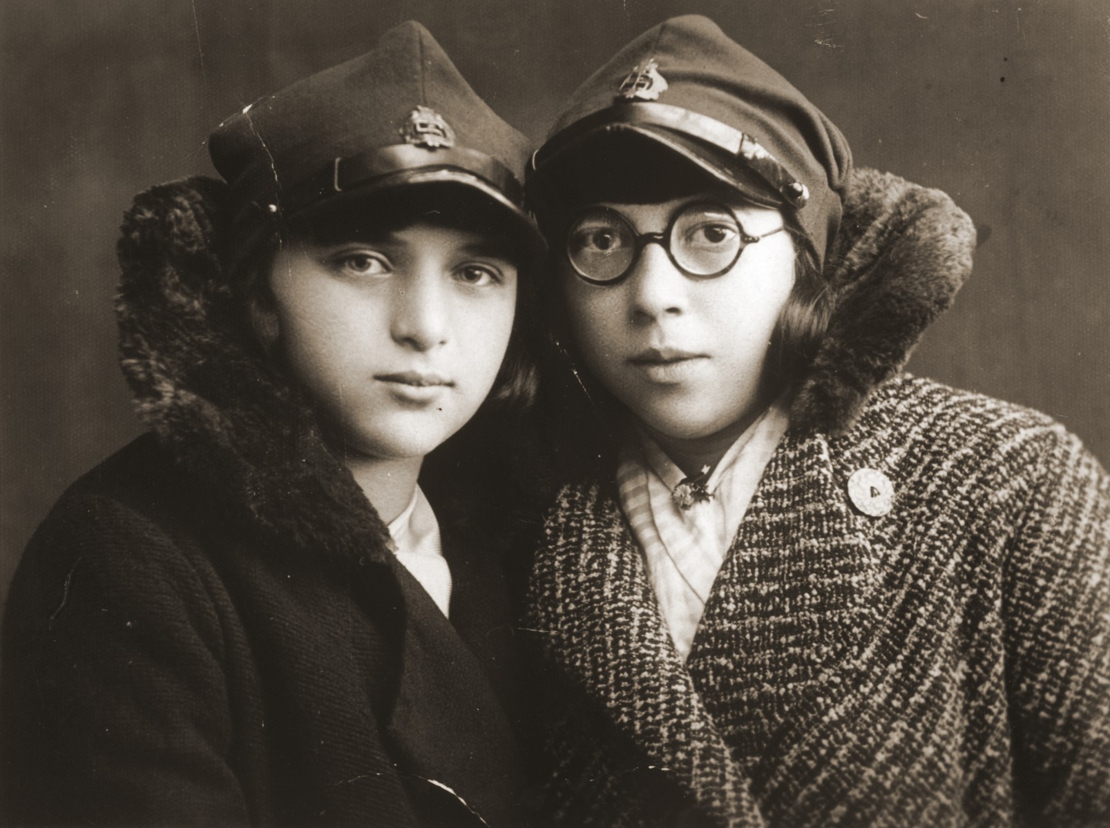 Felicja Berland poses with her friend Genia Laks wearing the hats of their school uniform.