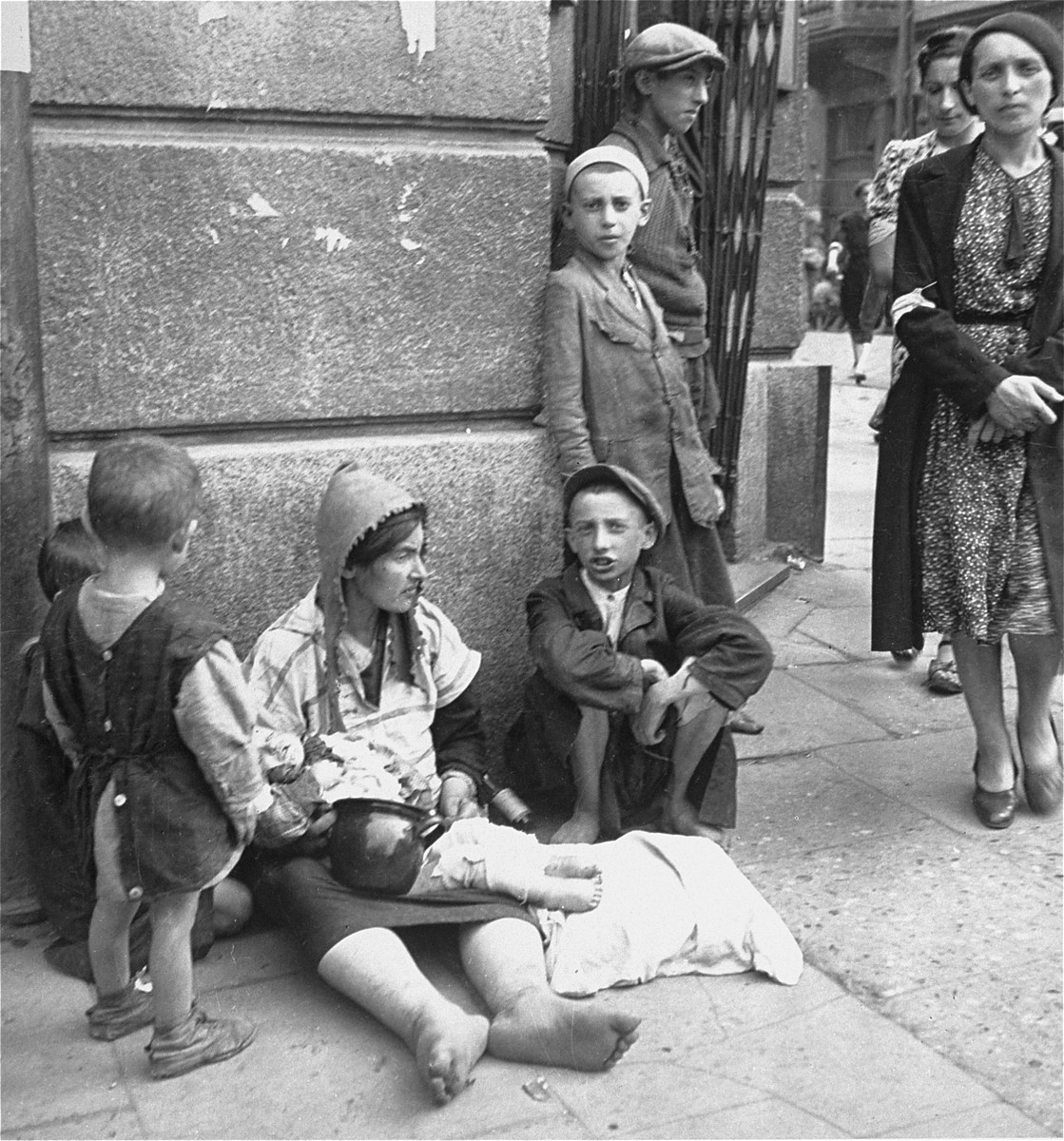 A destitute woman and her children on a street in the Warsaw ghetto.  

Joest's original caption reads: "This was a common sight and I had reservations about photographing it: a woman with child that was deathly ill, [who] sat barefoot and begging on the street.  She did not notice me."
