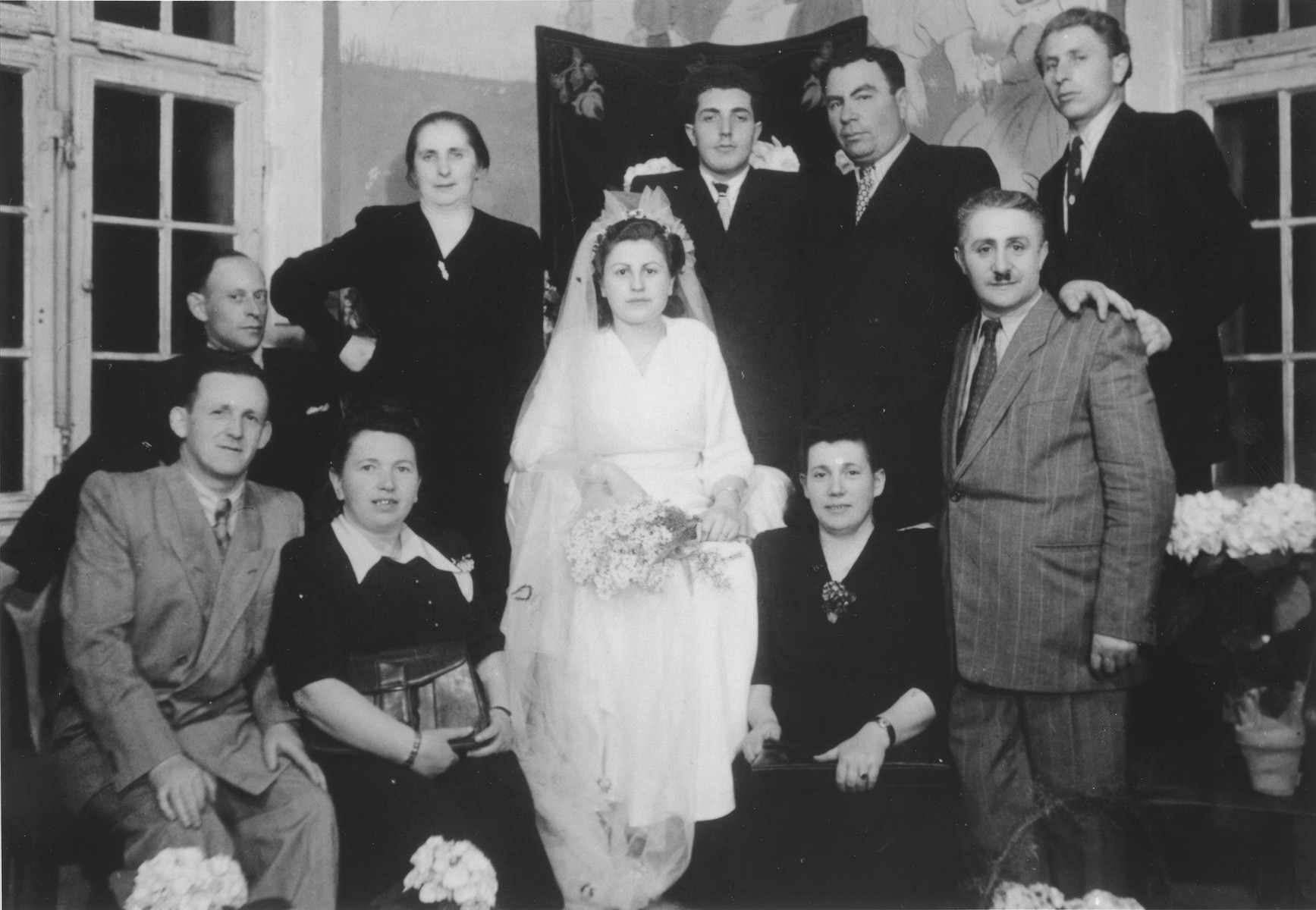 Group portrait of members of a wedding party in the Ulm displaced persons camp.

Among those pictured are Hershel and Chaja Rajs (bottom left).