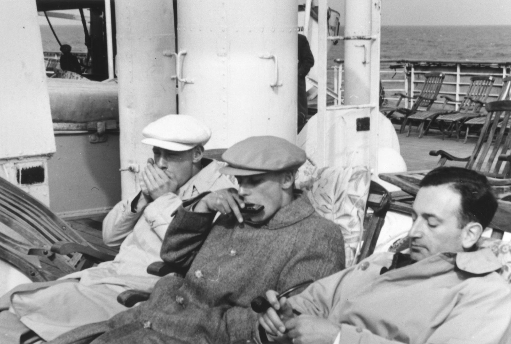 Three young Jewish refugees relax on the deck of the MS St. Louis.

Werner Lenneberg (right) naps while Fritz Buff (center) and another friend play harmonicas.