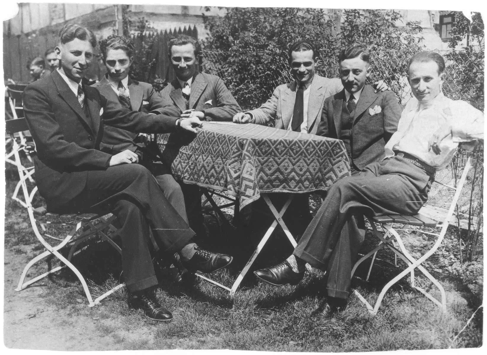 A group of young Jewish men wearing suits and ties sits outside around a table.

Among those pictured is Siegfried Kaiser.