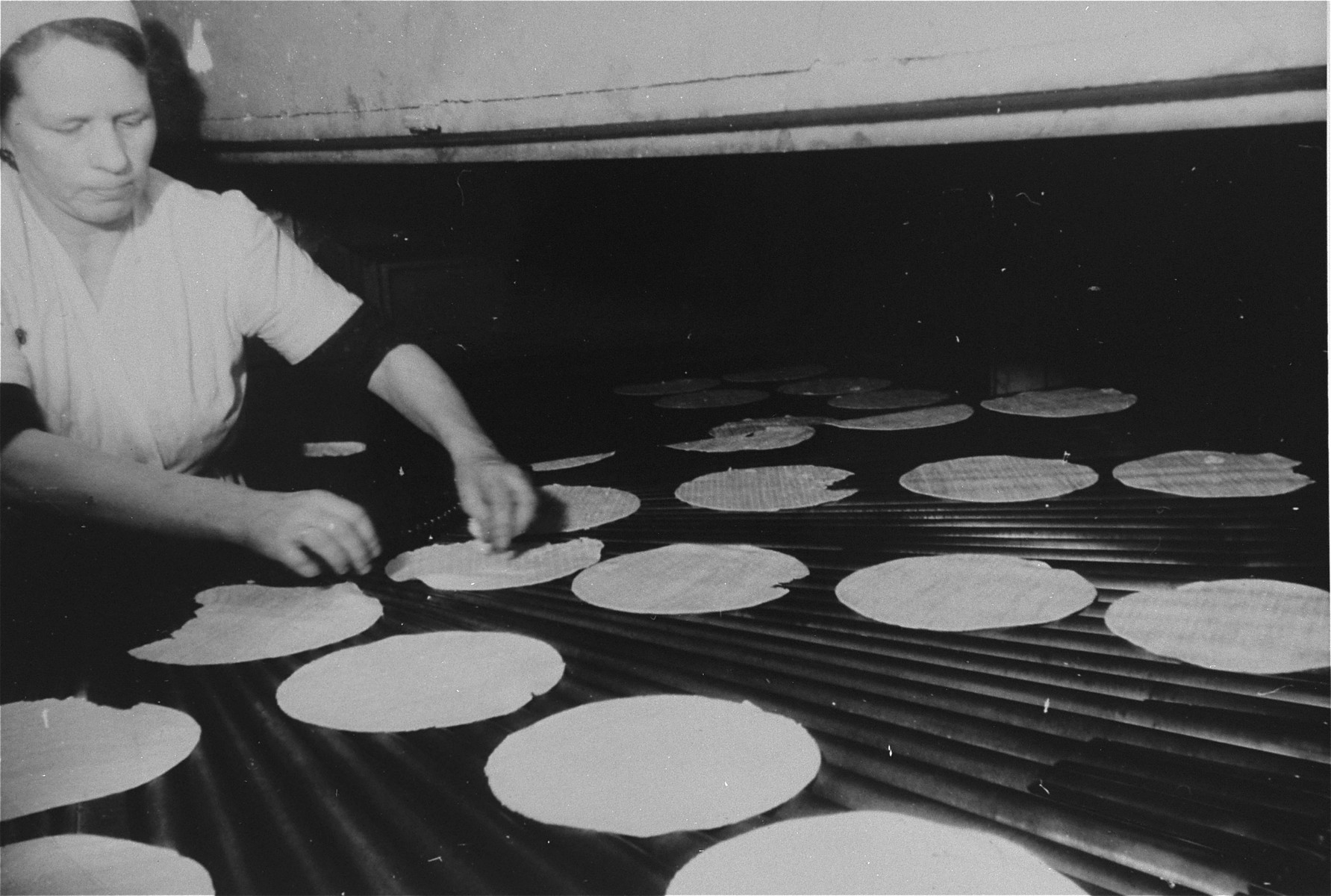 A woman bakes matzah at a bakery in Frankfurt that escaped destruction by the Nazis.