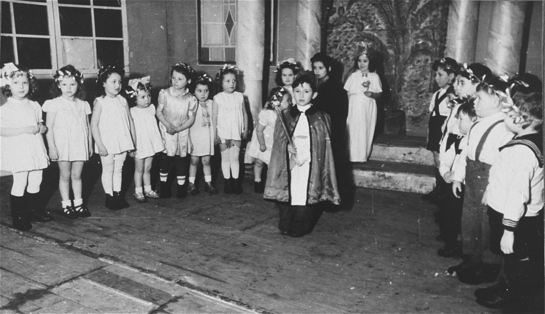 Young children perform in a Purim show in the Zeilsheim displaced person's camp. 

Fay Robinson (later Shlimovitz) on the far left, is the daughter of the photographer. She was born July 22, 1941 in Novaya Odessa, Ukraine. She went to Zeilsheim in 1945 and later emigrated to the United States in 1948.