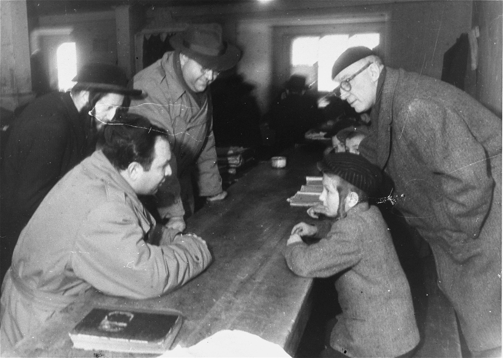 Saul Sorrin (left, foreground), director of UNRRA in the Munich area, visits a heder (religious primary school) at the Foehrenwald DP camp camp in the company of Frank  Kingdon (right), American journalist and politician, and Ted Feder (left), assistant director of the JDC in Germany.