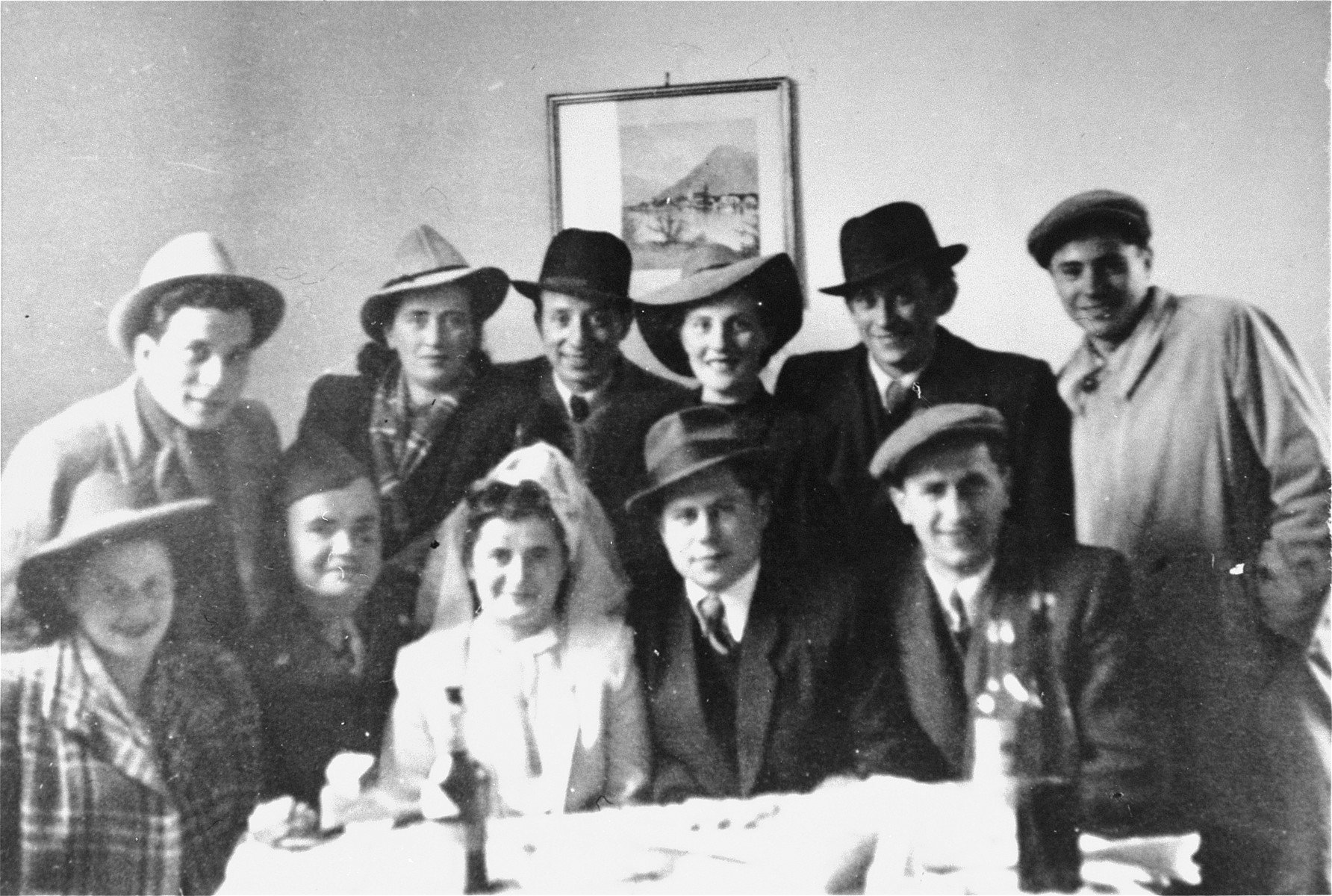 Group portrait of family and friends at the wedding of Regina and Sam Spiegel at the Foehrenwald displaced persons camp. 

Among those pictured is David Bajer (front row, far right), and Ester and Israel Korman (back row, second and third from the right).