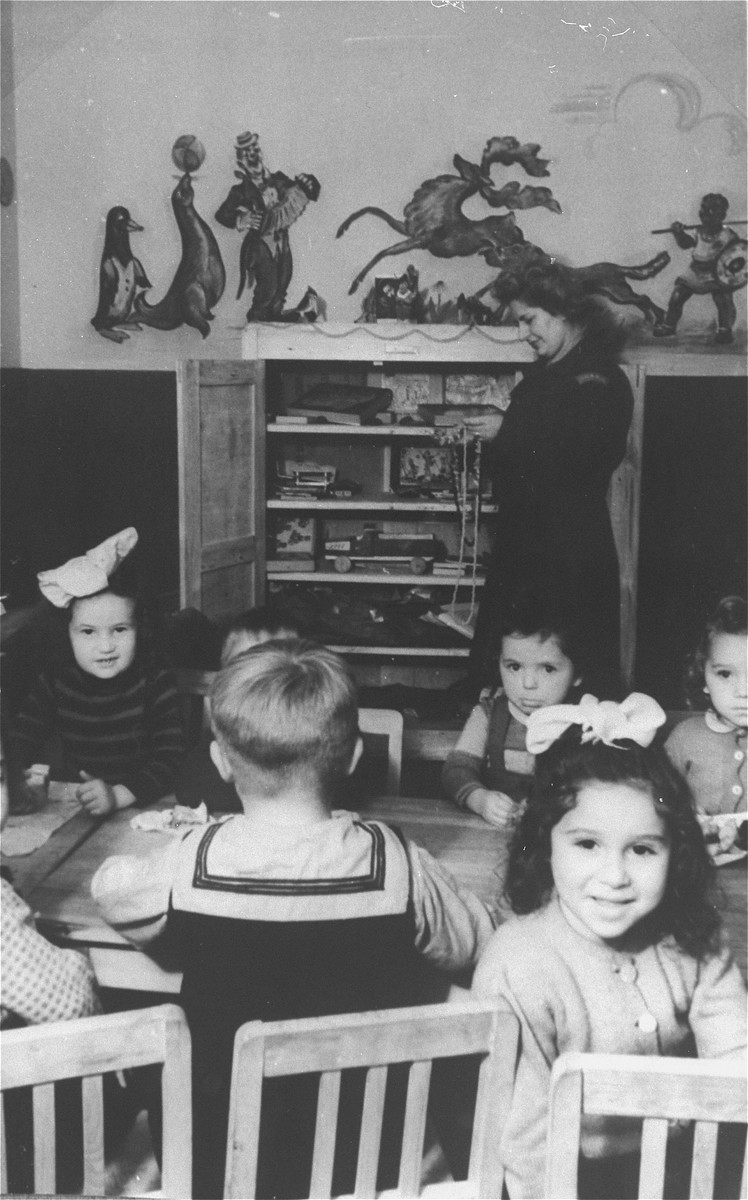 Young children sit around a table in the nursery school of the Zeilsheim displaced persons' camp.

The original caption reads: "In 1946, when the number of children increased, a nursery for preschoolers was organized."