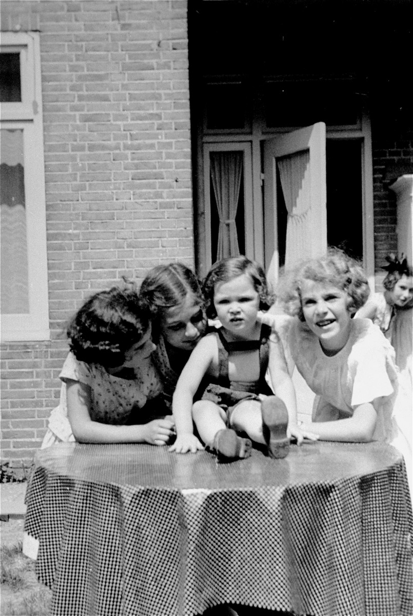 A group of young German Jewish refugee girls pose outside on a terrace in Amsterdam.  

Pictured from left to right are: Susanna Ledermann, Dolly Zeetroon, Hannah Toby, Barbara Ledermann and Hanneli Pick-Goslar (at the far right in the background).