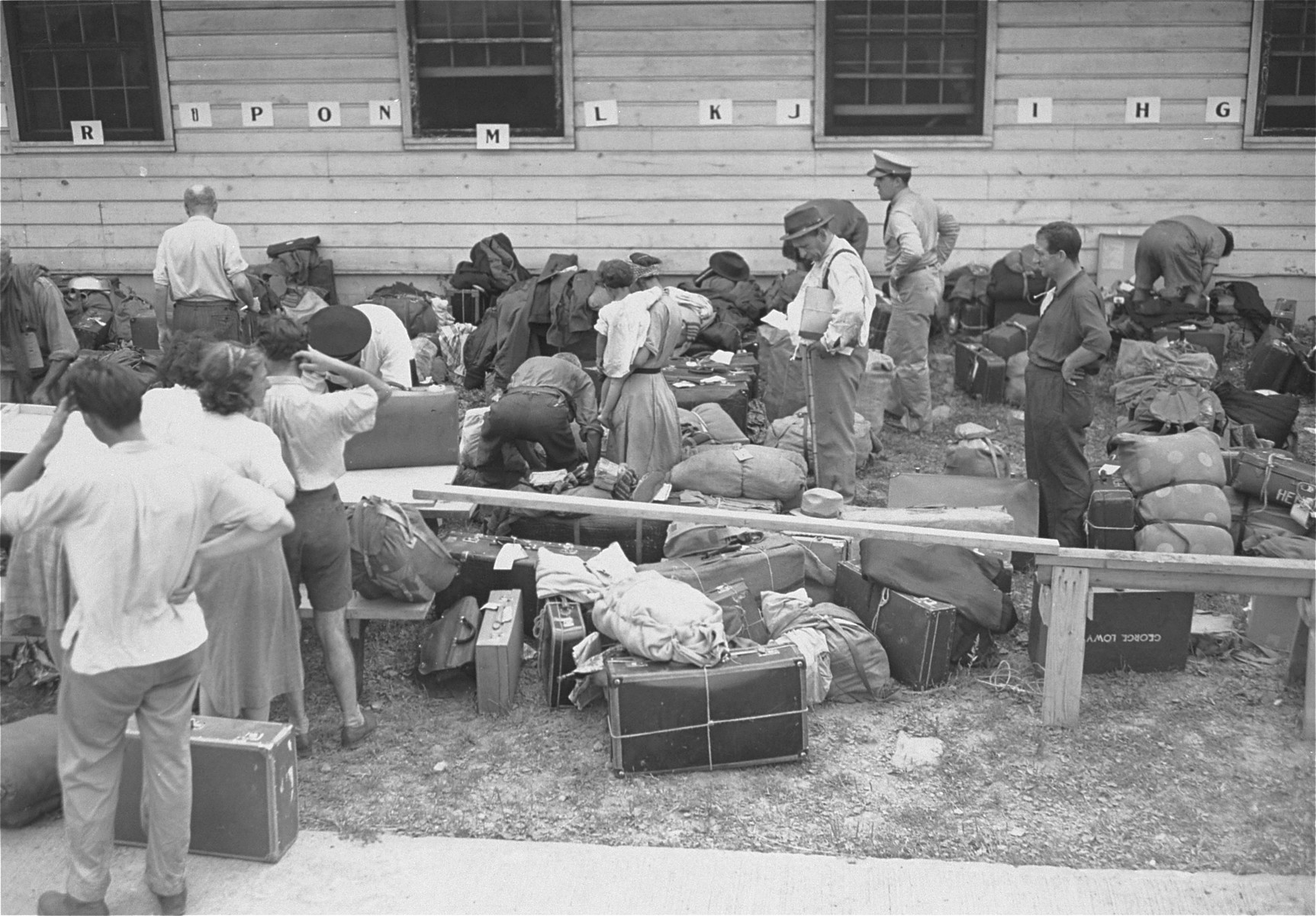 Newly arrived refugees are checked in at the Fort Ontario shelter by representatives of the War Relocation Authority and the U.S. Army; baggage is inspected by U.S. customs officials.