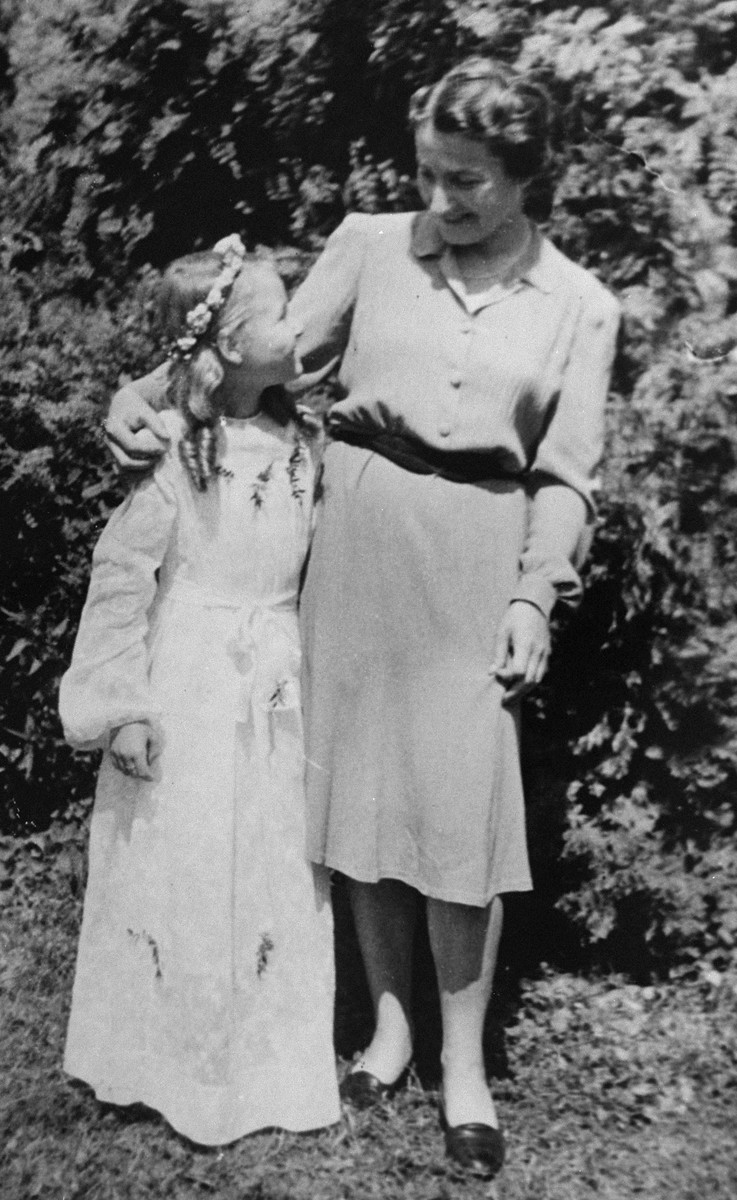 A Jewish mother poses with her daughter who is dressed for her First Communion.

Pictured are Laura Schwarzwald and her daughter Selma, who had lived in hiding as Polish Catholics during the war.