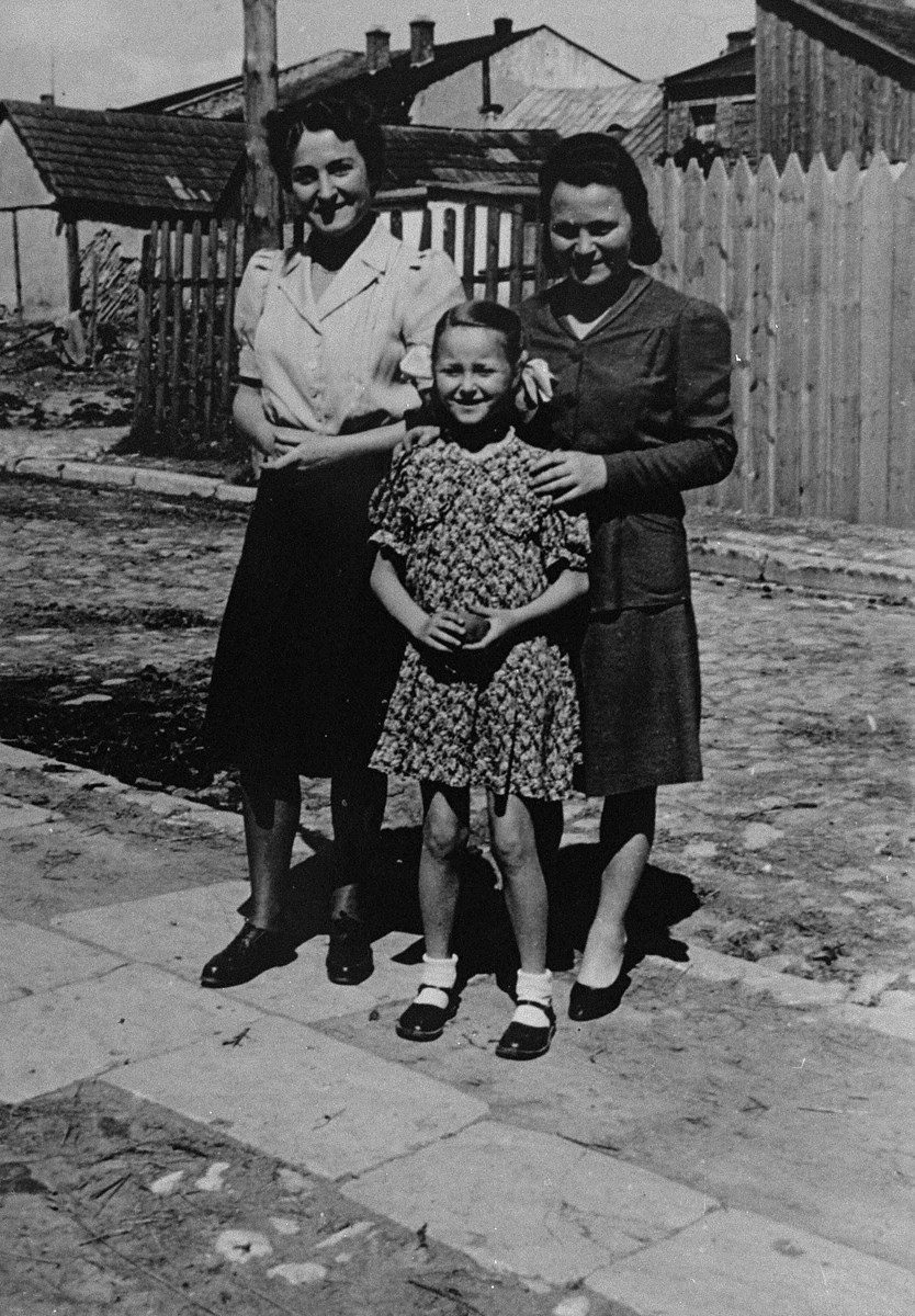 Jewish survivors pose on a street in Busko-Zdroj.

Pictured are Laura Schwarzwald (left) with her daughter Selma (middle) and sister Adela Litwak (right).