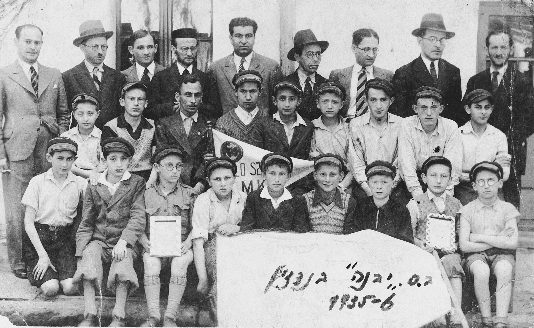 Group portrait of faculty and students of the Yavne Hebrew elementary school in Bedzin, Poland.

Among those pictured is Moniek Szeps (front row, second from the right) holding a framed portrait of the Polish president.  The inscription on the back of the photo reads, "As a memento to dear Moniek wishing that you will visit often your Mizrachi teacher, Euteniusz Pejsachowicz."  It is followed by a list of student signatures: H. Przymowski, M. Lustiger, Ksylek Hinigman, Moniek Radzynski, Olek Maka, H. Rechnic, M. Rechnic, Braun.