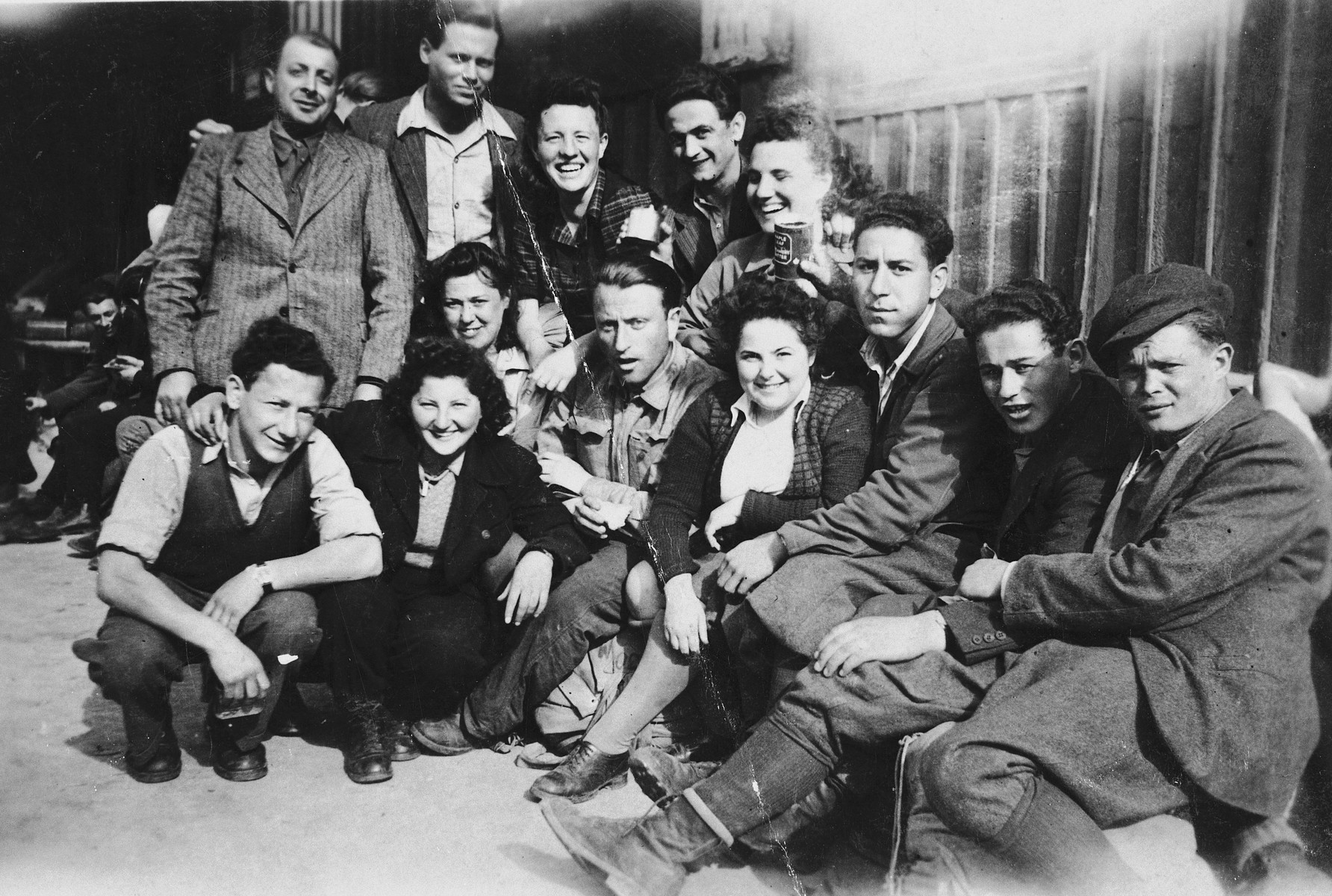 Group portrait of young Jewish DPs who are seeking to immigrate to Palestine illegally, at a way station near the Italian border.

They await permission to cross the border and transport into Italy.  Seated in the front row from left to right are: Moniek Szeps, Goldi Silberstein, Levi Danielski, unknown, Meni Szmulewicz, Mendel Ingber and Yehezkel (Nandor) Tesler.  In the second row, from left to right are: Zlotnik, Arik Ofner, Hana, Mojszale Wyszogrodzki, Haja Danielski; seated above Goldi Silberstein is Hana Ingber.