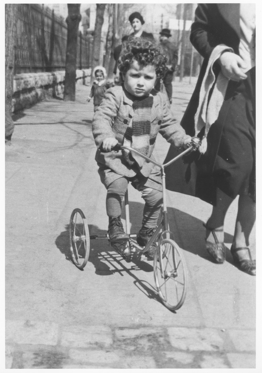 A young Jewish boy rides his tricycle down a street in Krakow.

Pictured is Lolush Gerstner, who was later killed in Auschwitz.