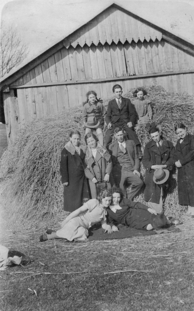 A group of Jewish youth pose on a haystack at a summer camp in Raczyna, Poland. 

Among those pictured is Basia Gurfein (bottom, right).