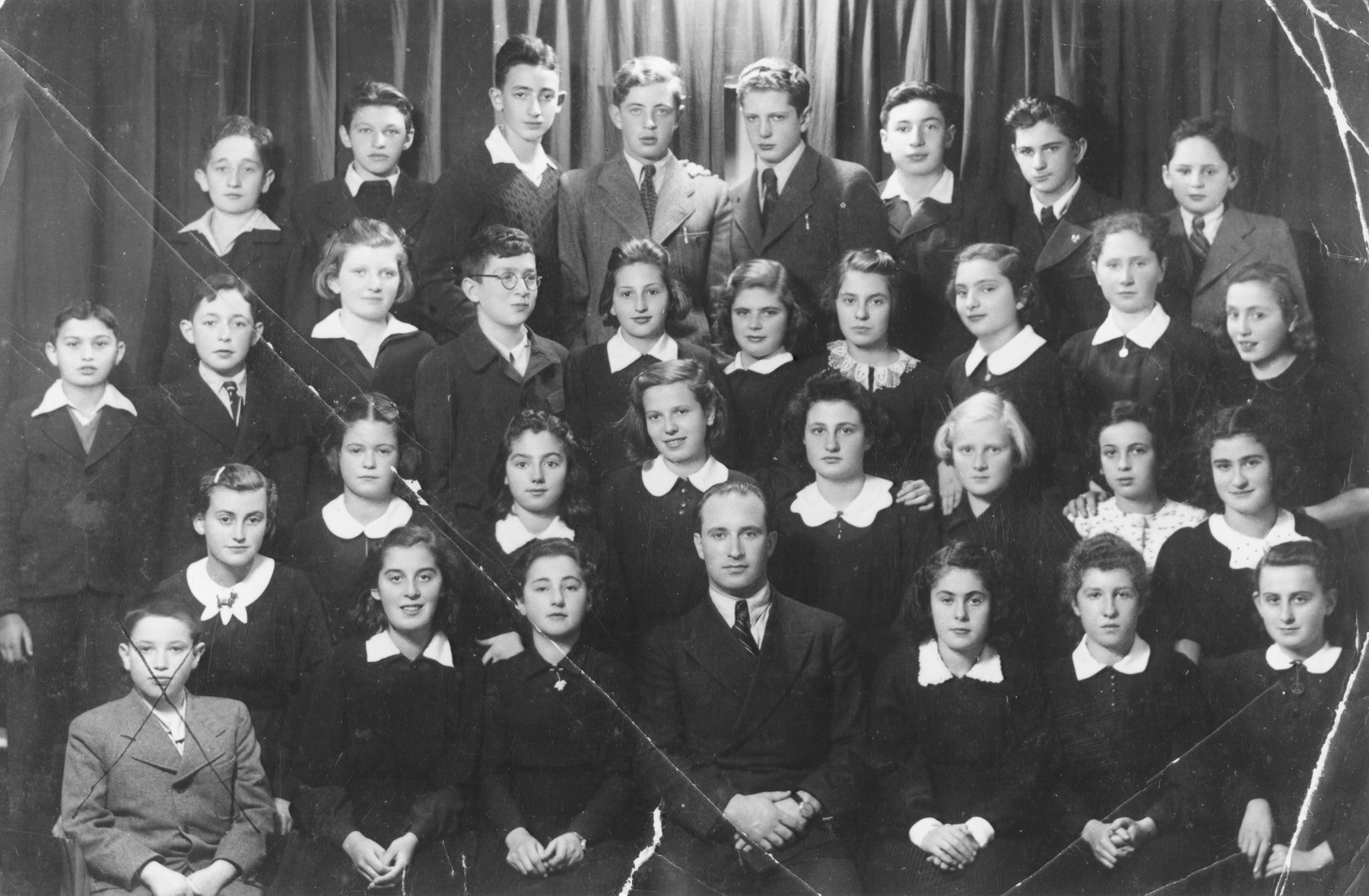 Group portrait of the students of the Schwabes Hebrew gymnasium in Kovno, Lithuania.

Among those pictured are Ben Zion (Nolik) Schmidt (top row, second from the right), Freda (Shottenstein) Schatenstein (second row from bottom, fourth person from right), and Ezra Jodidio (back row, fourth from the left).