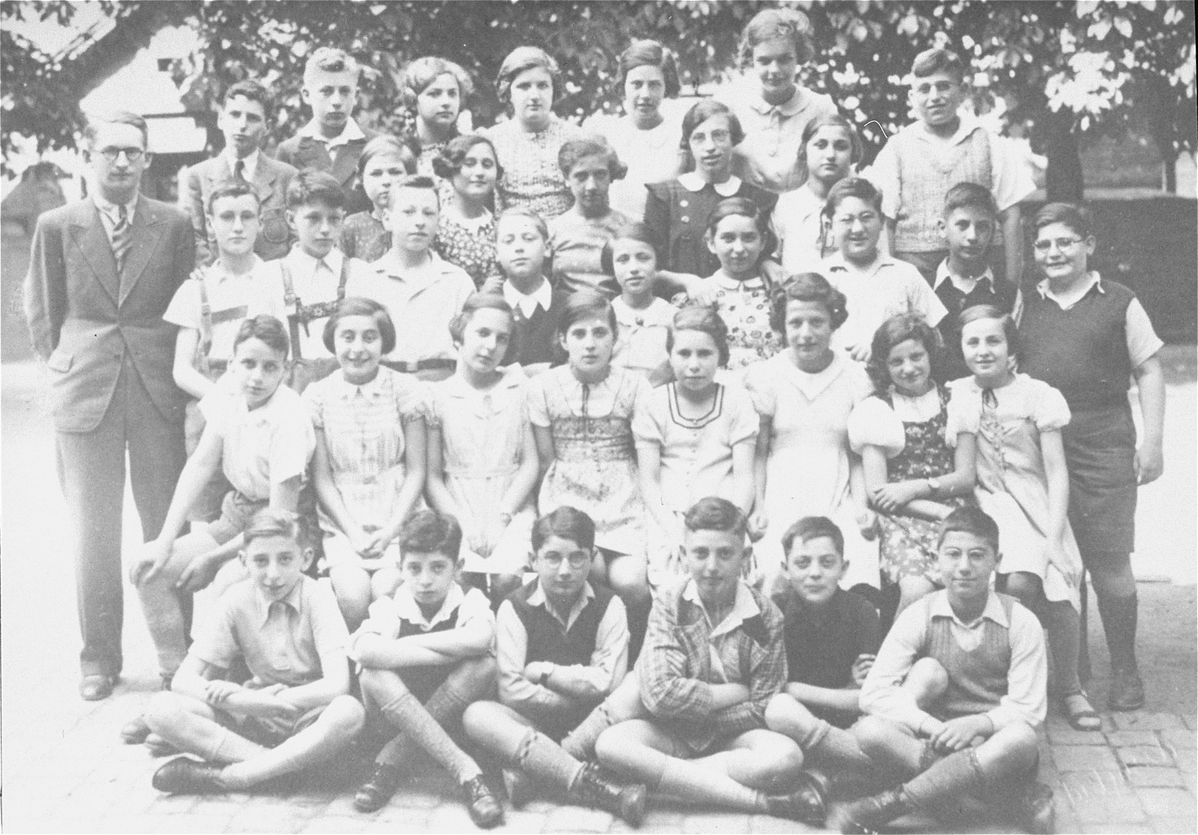 Group portrait of pupils in the seventh grade at a Jewish school in Karlsruhe, Germany that had been relocated to one floor at the 'Holzbodengymnasium' a special school for mentally disabled children. 

Among those pictured is the teacher, Max Ottensoser.  Also pictured is Suse Heidenheimer (later Steinhardt), 
second row from the front and the fourth girl from the right.  Louis (Ludwig) Maier is pictured in the top row, second from the left.  Julius Hirschberger is on the borttom row, far right and Walter Baer is in the third row, third from the left.