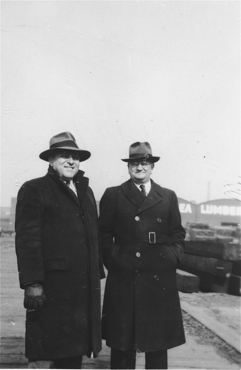 Two men responsible for acquiring the President Warfield standing in a dockside lumber yard in Baltimore, where the ship was prepared for its trip to Europe.

Pictured on the left is George Levin.