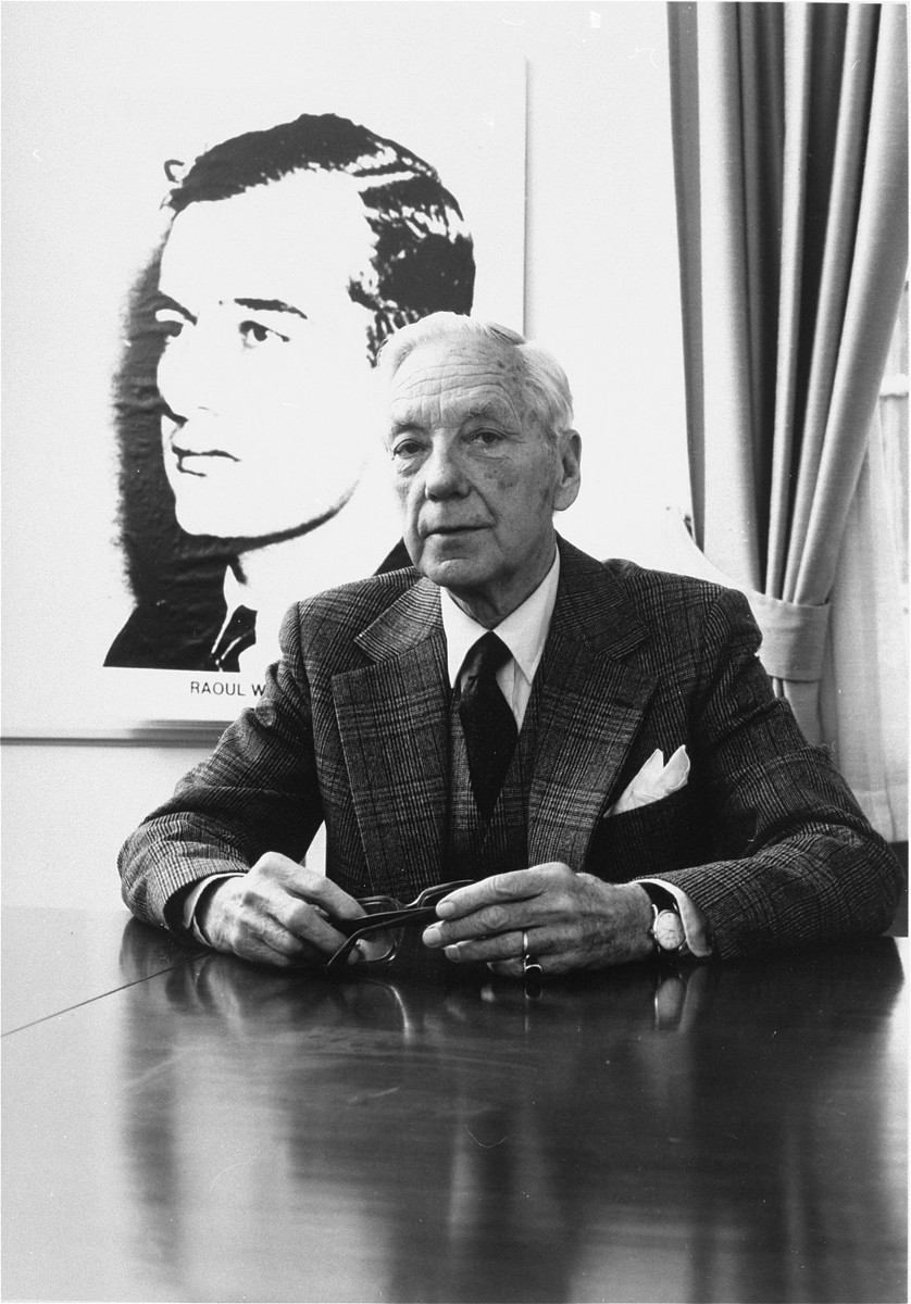 Per Anger poses in front of a portrait of Raoul Wallenberg in his office.