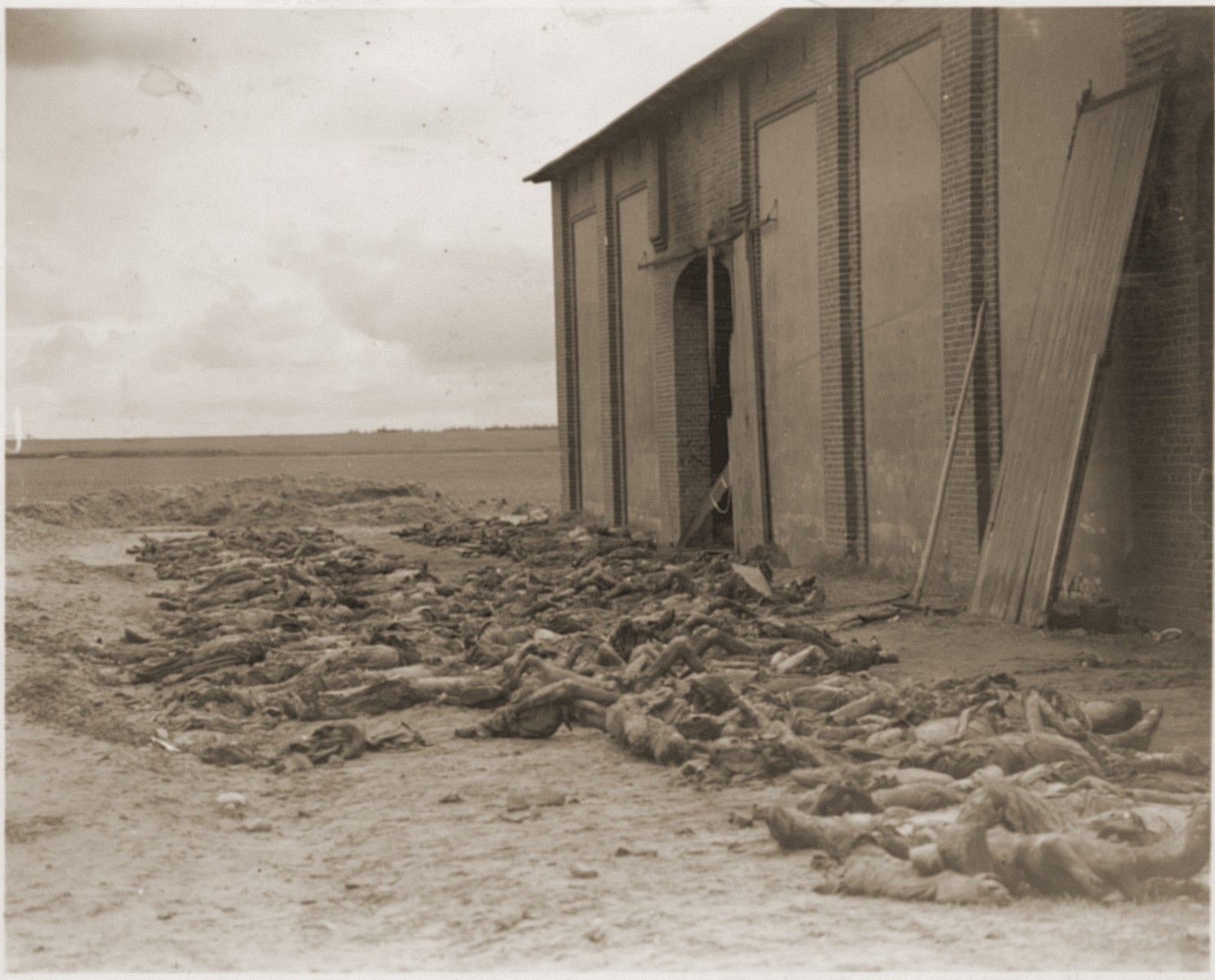 The bodies of concentration camp prisoners killed by the SS lie outside of a barn near Gardelegen.  

The original caption reads "German civilians bury victims of Nazi sadism.  The charred bodies of victims of Nazi brutality lie waiting for their reburial by civilians [from] nearby Gardelegen, Germany."