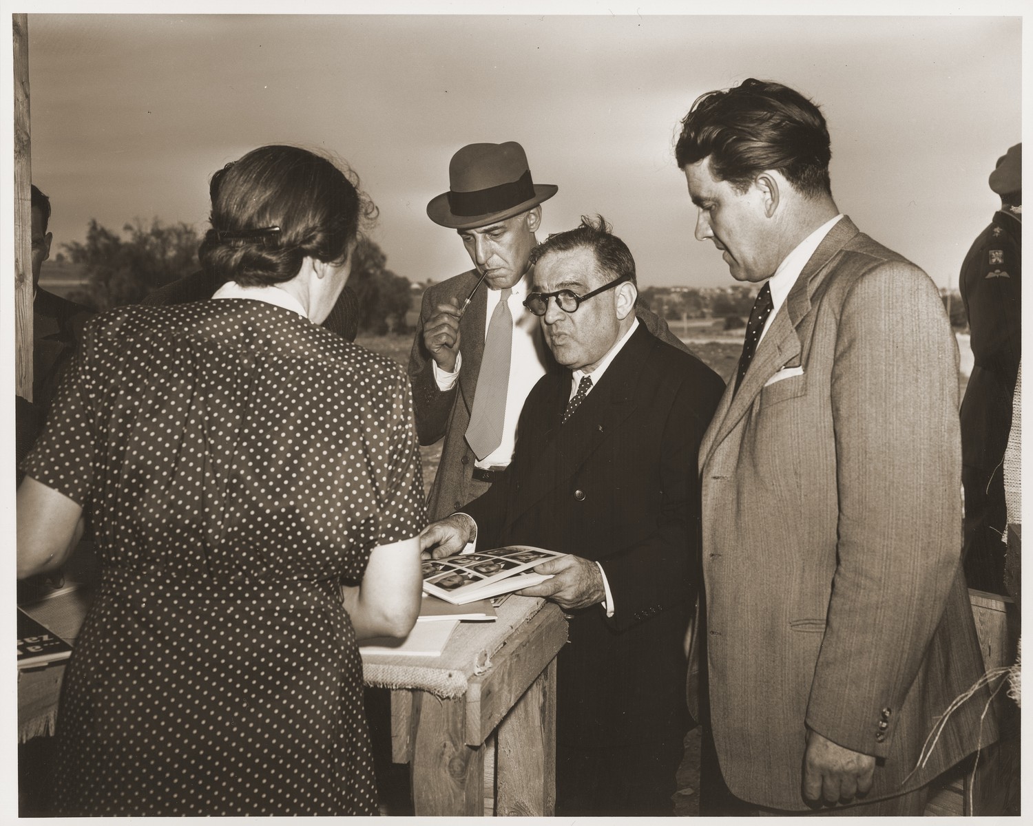 A survivor of the Lidice massacre shows Fiorello LaGuardia an album of photographs depicting the Nazi atrocity of June 1942, during an official visit by the UNRRA director to Lidice.

Also pictured is Laurence Steinhardt, U.S. Ambassador to Czechoslovakia (next to LaGuardia smoking a pipe), and Vaclav Majer, Czech minister of Food (to the right of LaGuardia).