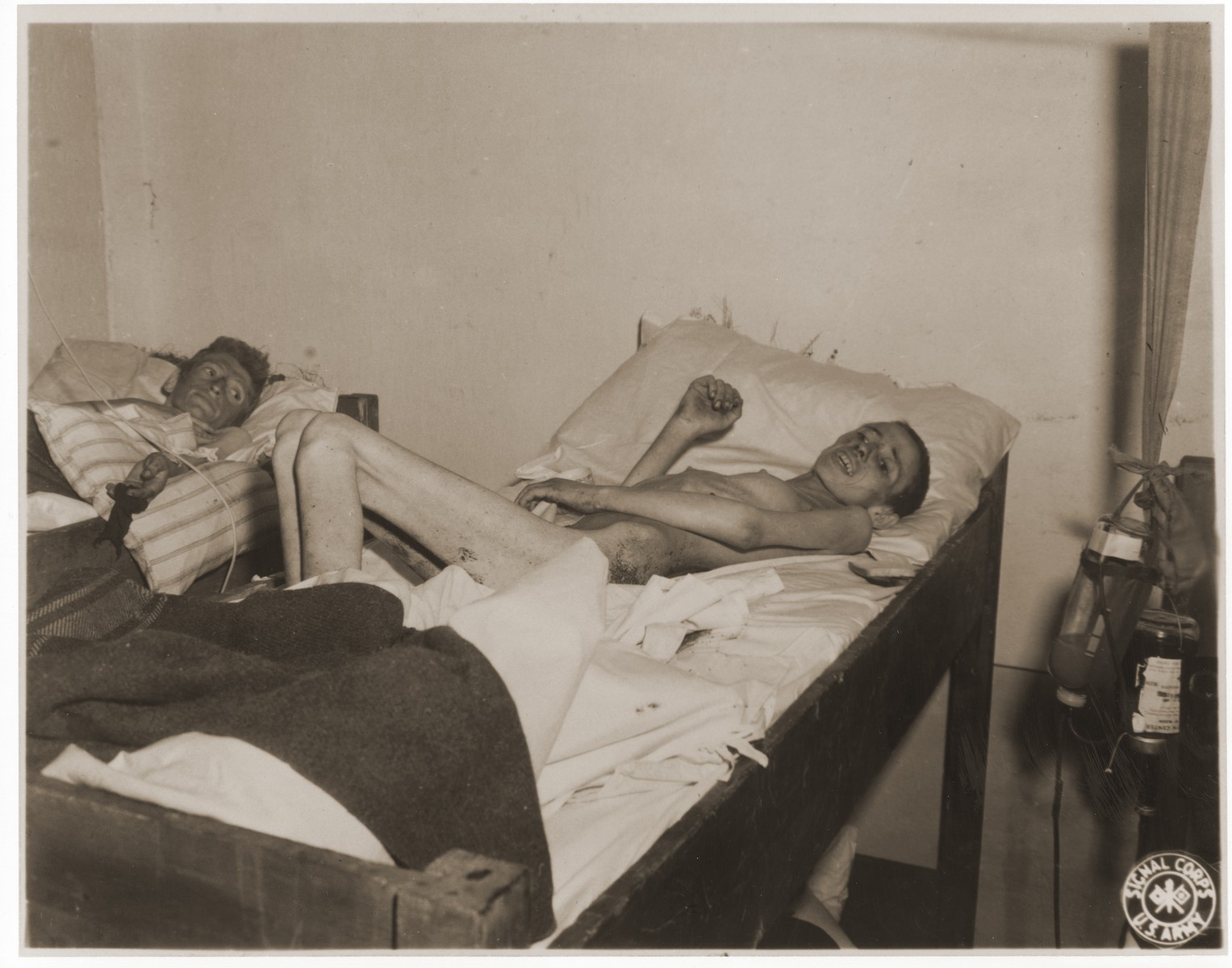 An emaciated female Jewish survivor of a death march lies in an American military field hospital in Volary, Czechoslovakia.

Pictured in the center is twenty-year old Serin Davidairco.