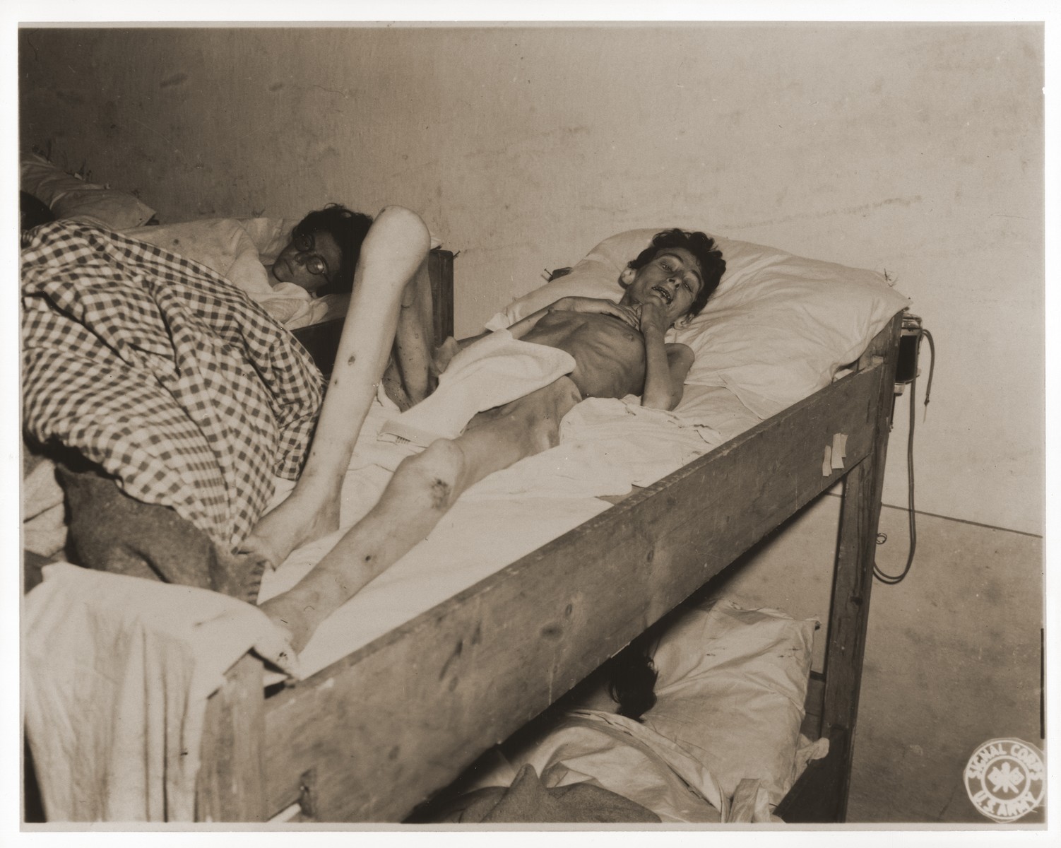 An emaciated female Jewish survivor of a death march lies in bed at an American military field hospital in Volary, Czechoslovakia.

Pictured is thirty-two-year-old Lilly Rosenberg.