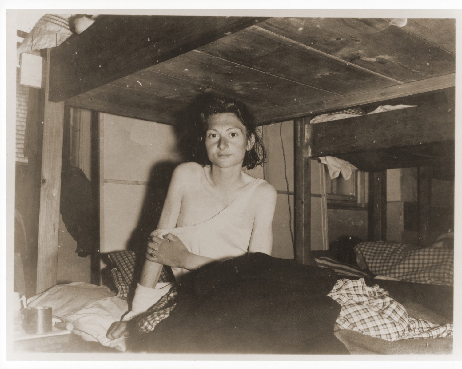 An emaciated female Jewish survivor of a death march sits up in bed at an American military field hospital in Volary, Czechoslovakia.

Pictured is twenty-two year old Amalie Mary Reichmann.
 
The original caption reads "Before and After Enslavement: Weakened by malnutrition after a forced march of 30 days during Nazi enslavement, this unidentified girl was found in Volary, Czechoslovakia, by units of the 5th Division, U.S. Third Army.  She was in a group of 150 persons, twenty of whom died daily  during the march."