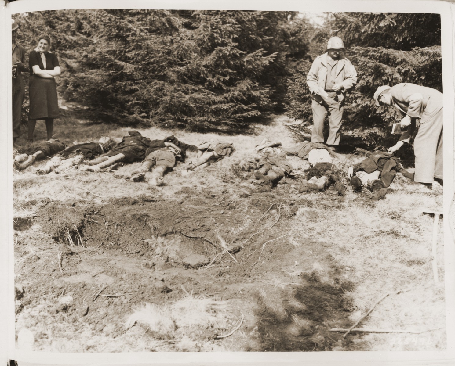 A medic with the 5th Infantry Division, 3rd U.S. Army, checks the bodies of Jewish women exhumed from a mass grave in Volary.  The victims died at the end of a death march from Helmbrechts, a sub-camp of Flossenbuerg.