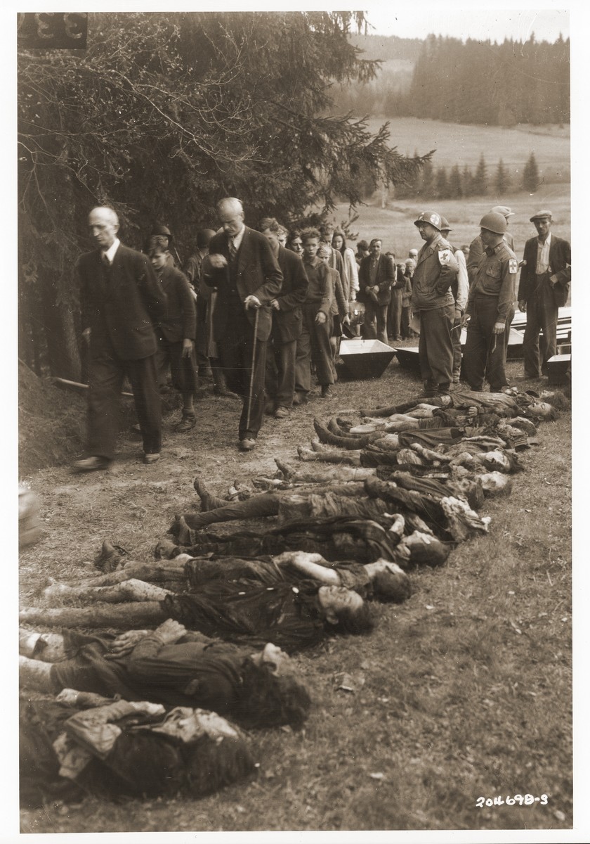 Captain Nathan Knoll and other American medics, supervise German civilians as they file past the bodies of Jewish women exhumed from a mass grave in Volary.  The victims died at the end of a death march from Helmbrechts, a sub-camp of Flossenbuerg.

The 14 year old boy marching in the front is Boris Surm.