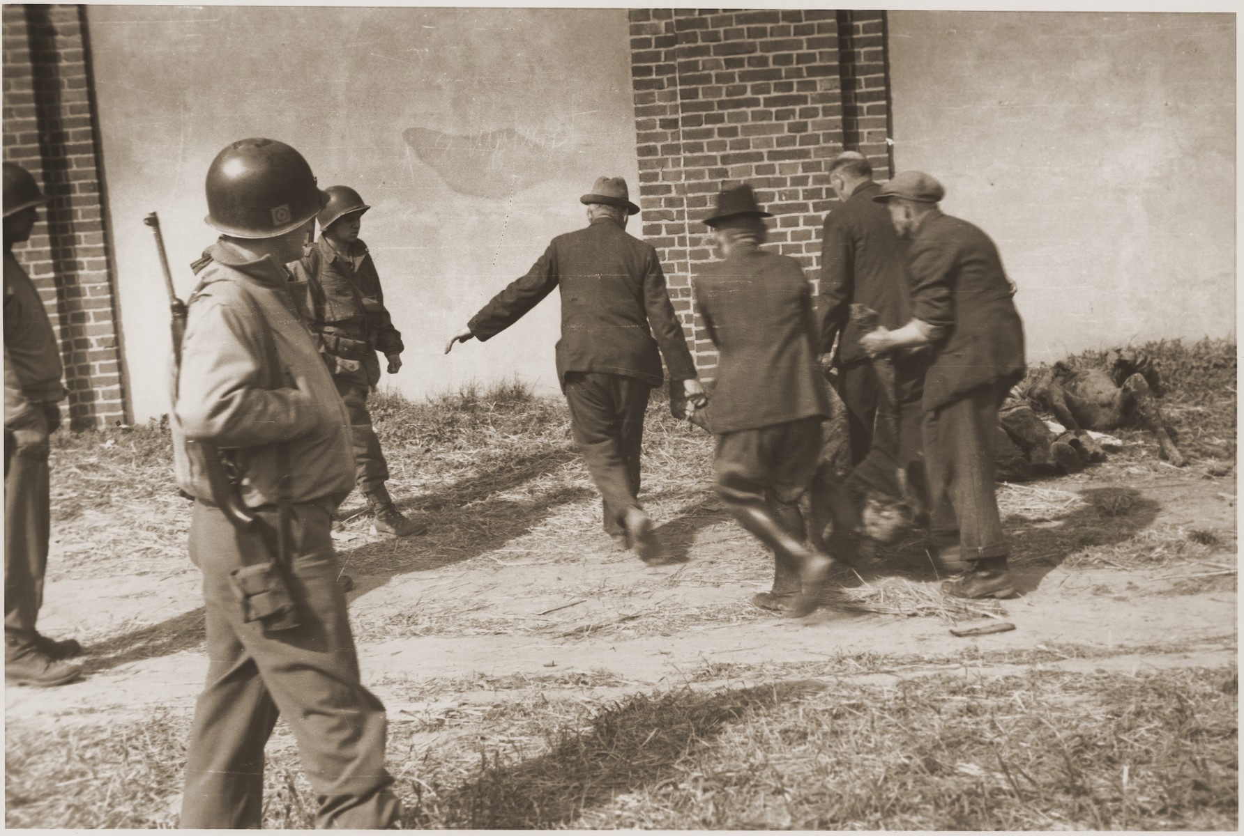 Under the supervision of the Ninth U.S. Army, German civilians are forced to remove the charred corpses of prisoners from a barn outside of Gardelegen for burial in mass graves.
