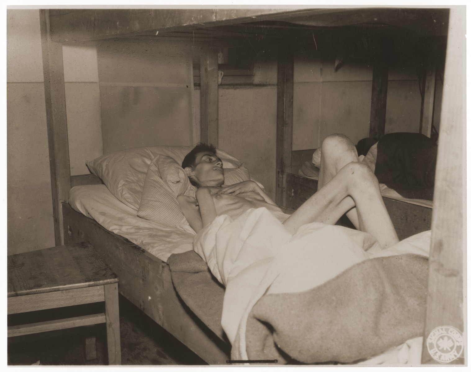 An emaciated female Jewish survivor of a death march lies in an American military field hospital in Volary, Czechoslovakia.

Pictured is twenty-nine year old Amilia Langer.