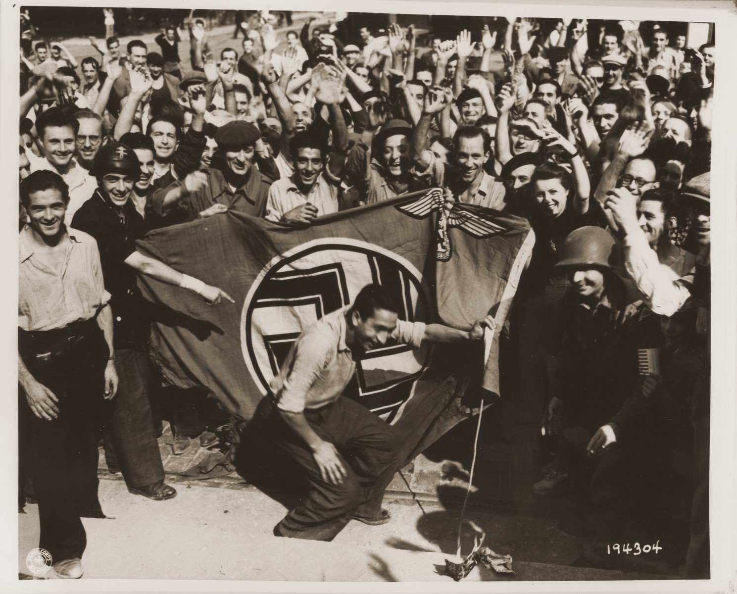 A crowd celebrating the liberation of Marseilles sets fire to a Nazi flag that had been flying over the police building.