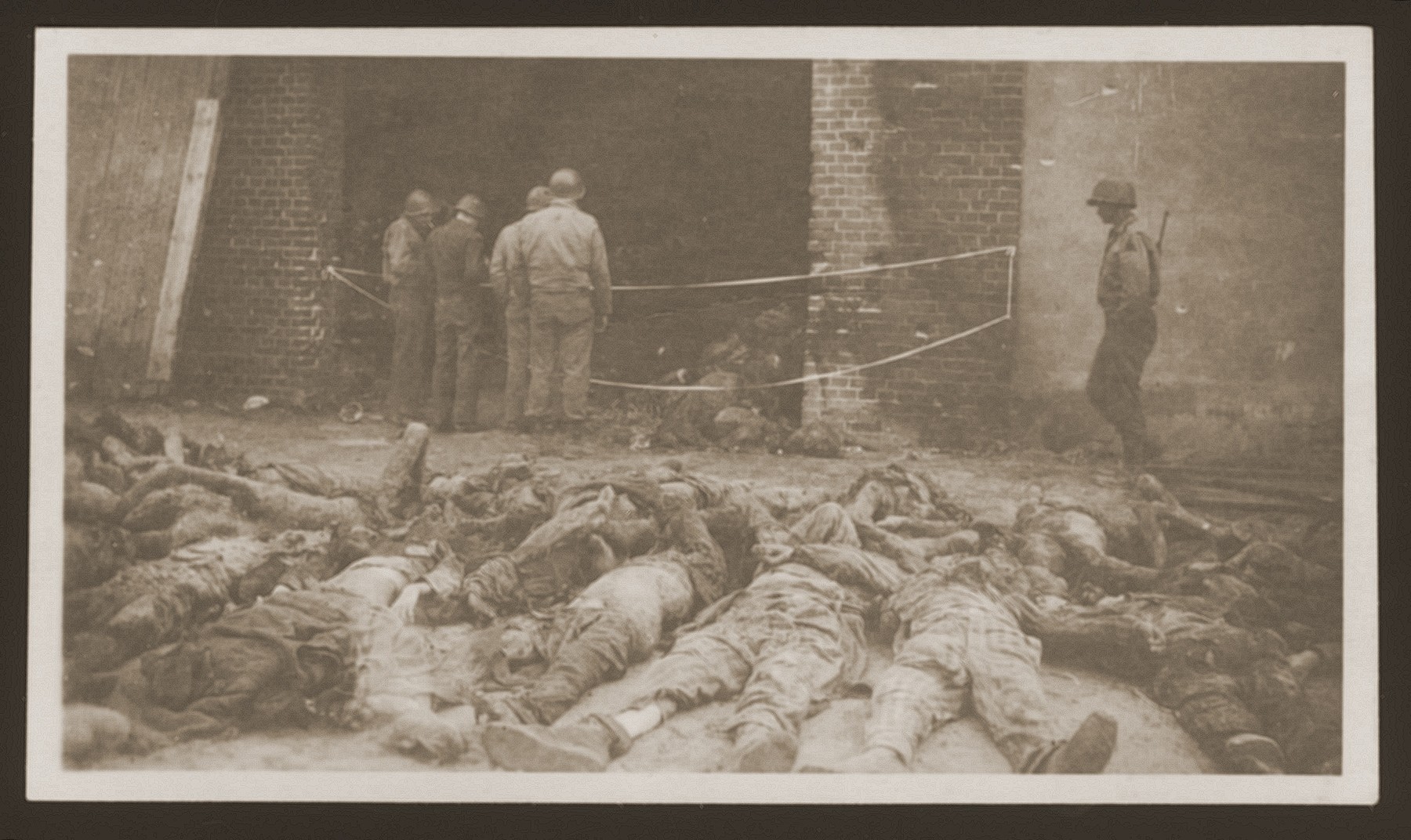 American soldiers look at the charred bodies of prisoners burned alive by the SS in a barn outside of Gardelegen.  In the foreground lie bodies already removed from the barn.
