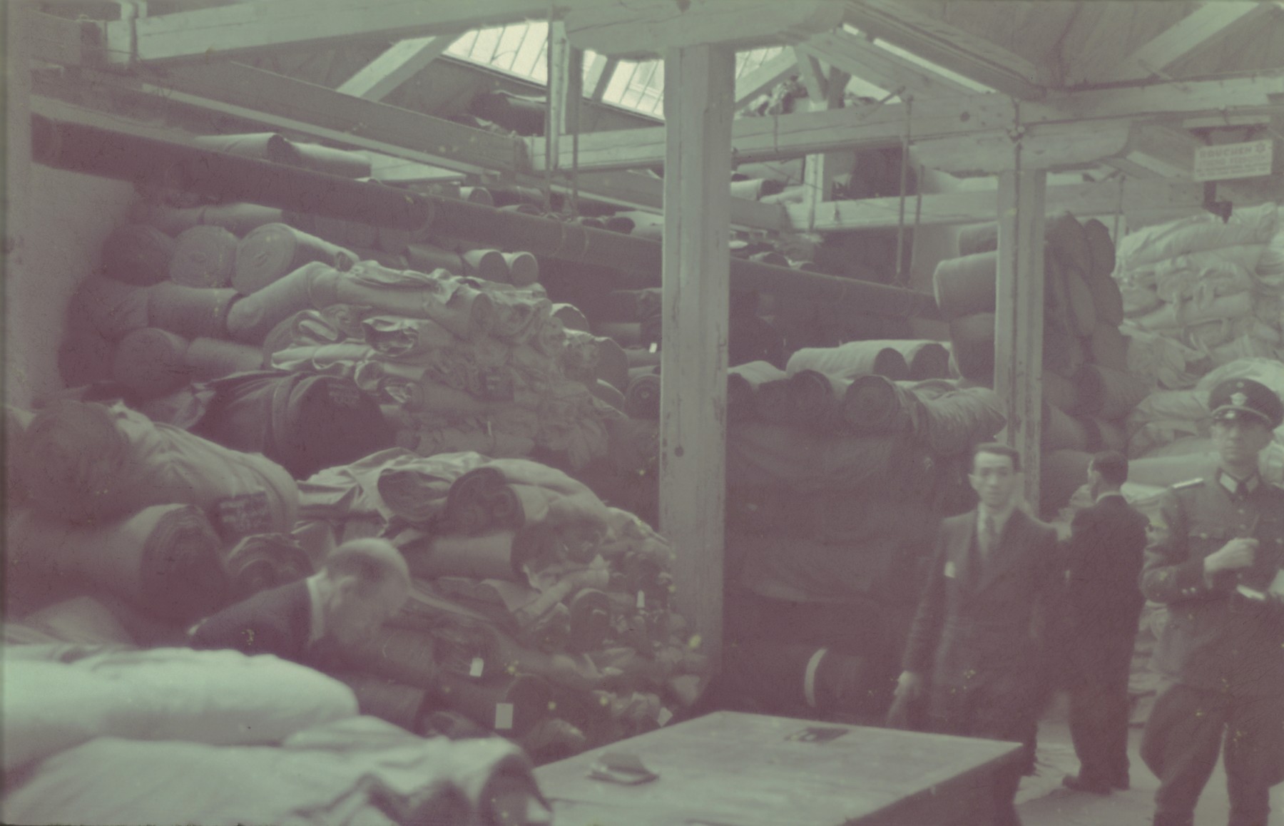 A German official inspects the textile storeroom in the Lodz ghetto.

Original German caption: "Getto, Litzmannstadt, Lager fur textilien" (textile warehouse), #194.