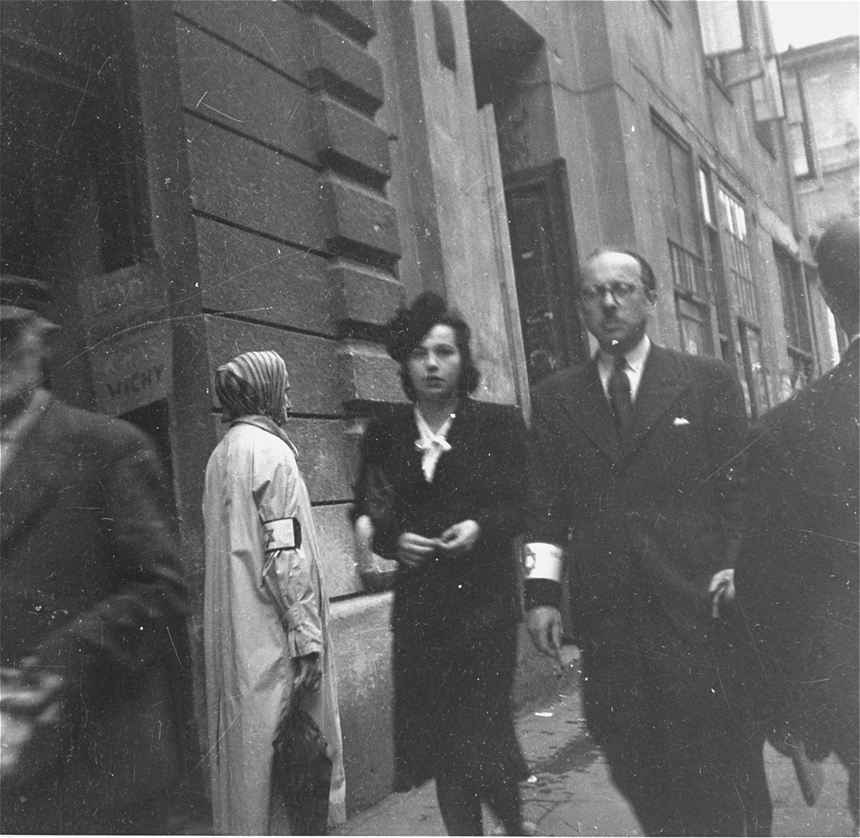 A well-dressed couple on the street in the Warsaw ghetto.  

Joest's original caption reads: "I was amazed that in the ghetto I occasionally met "better people" like this man with his pocket hankerchief and umbrella and his fashionably dressed wife with a hat and jewelry.  I asked myself how they were able to live, and a year later, I asked myself if they were still alive."