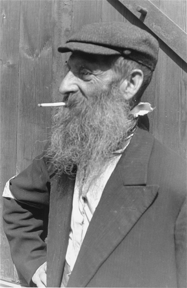 Portrait of a bearded Jewish man smoking a cigarette in the Warsaw ghetto.