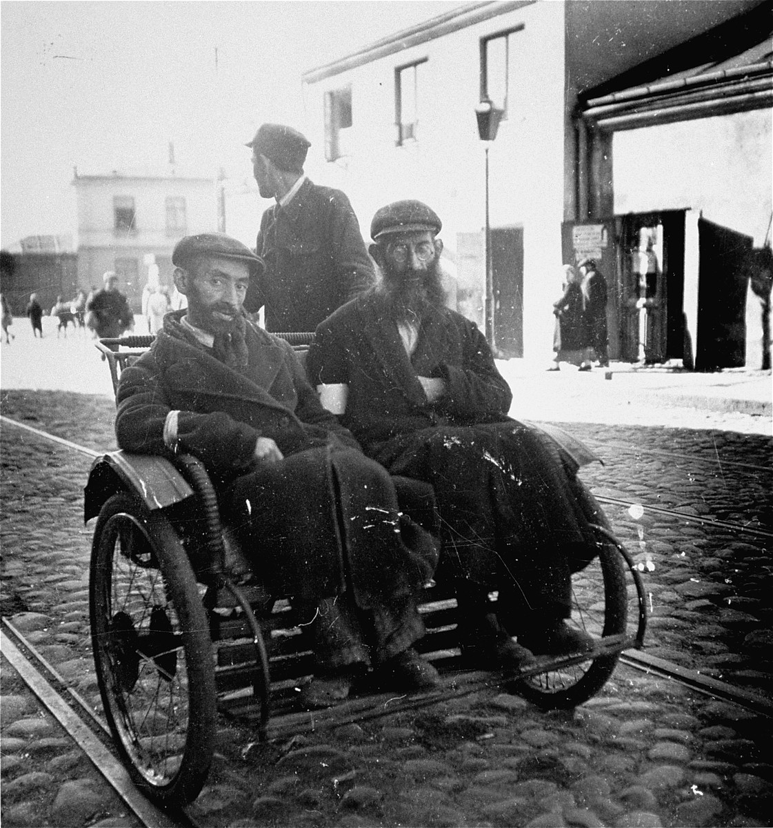 Two religious Jewish men travel by rickshaw in the Warsaw ghetto.  

Joest's caption reads: "I had earlier never seen human beings used as a means of transportation.  I thought such a thing only existed in India."