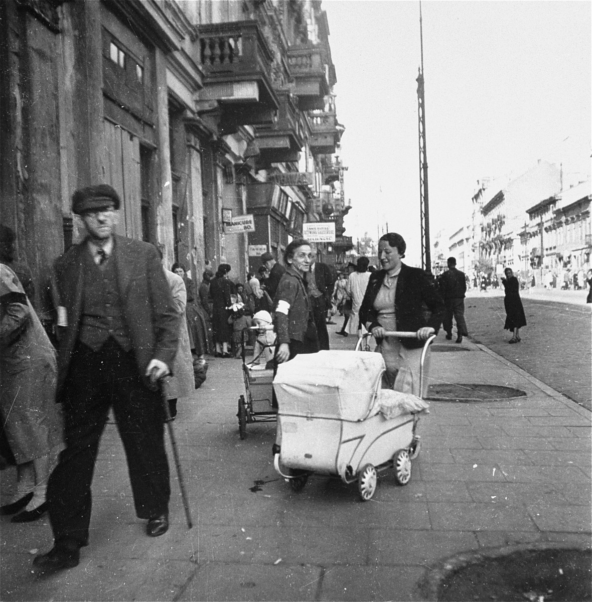 Two Jewish mothers on Leszno Street in the Warsaw ghetto.  

Joest's caption reads: "It looked like a normal street scene.  Furniture stores, a manicure shop, two women with baby carriages . . . If only the armbands were not visible.  I believe this was the Gerichtsstrasse, which was earlier called Leszno Street."