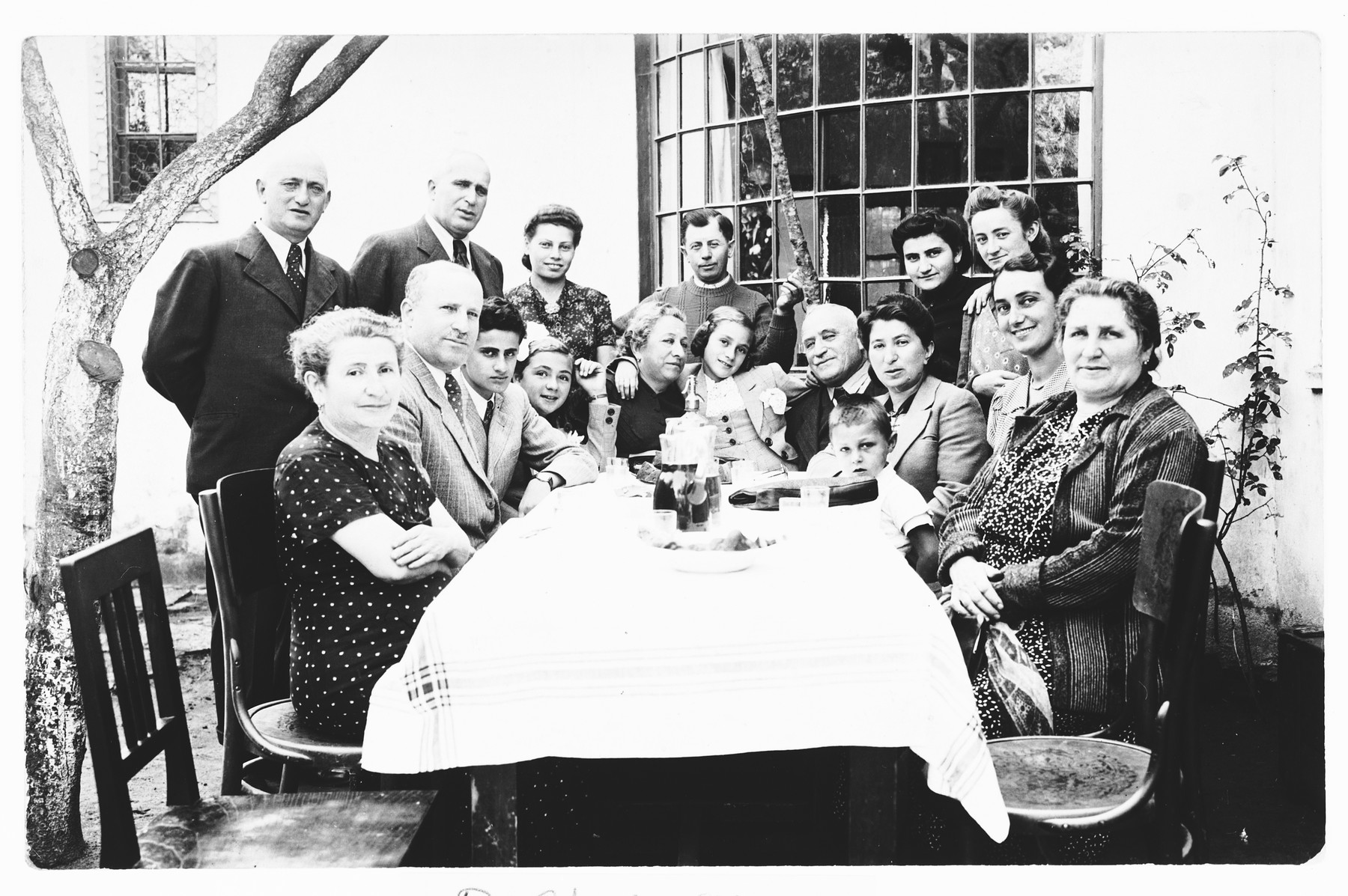 The extended Krasso and Spitzer families pose outside around a table at a family gathering shortly before the start of the war.

Among those pictured are Miriam Spitzer (fourth from the left), her mother Ilonka Spitzer (second from the right) and sister Leah (center next to her grandparents).