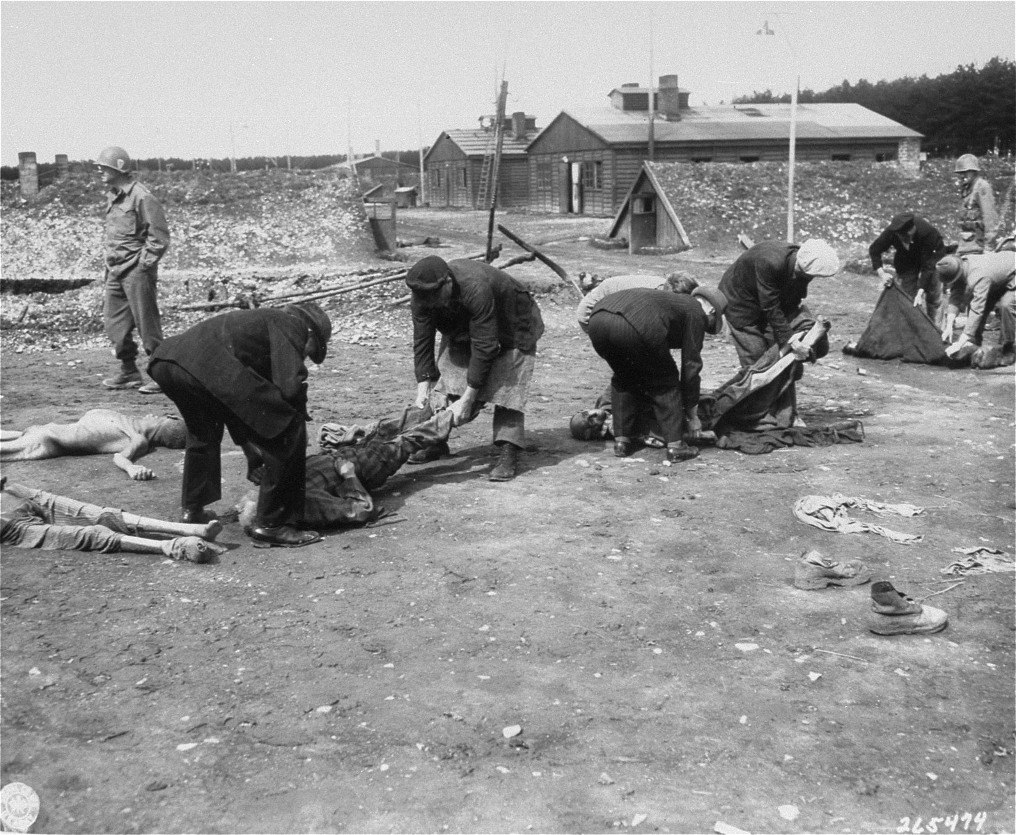 German civilians from the town of Hurlach move corpses found in Kaufering IV to mass graves for burial.

Original caption reads, "German Civilians from Landsberg, Germany, are carrying the dead bodies of Russians, Poles, French, and Jewish prisoners,  starved and burned to dead by German S.S. troops at the Stalag #4 concentration camp."