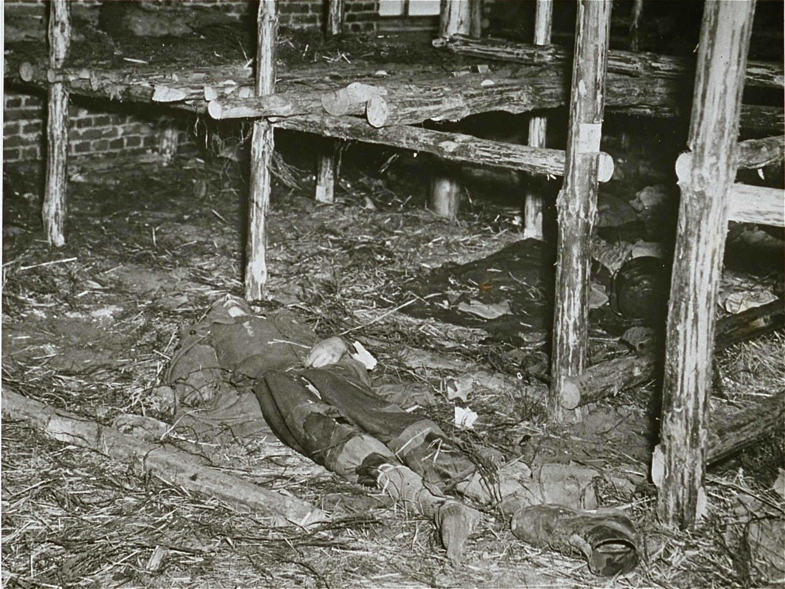 The body of a former prisoner lies on the ground of a barracks of the Woebbelin concentration camp.

Original Caption: "This camp, recently captured by troops of the US Ninth Army, had prisoners who starved to death. Here one lies on the floor in the living quarters of the prisoners."