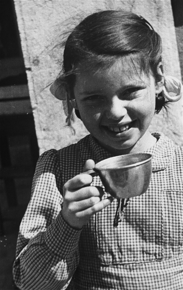Portrait of a Jewish refugee child holding a cup at the Hotel Bompard internment camp.

This photo is from a series taken by Julia Pirotte, a native of the region, who was invited by the "camp" commander to photograph the women and children because "[the] Joint [Distribution Committee] was organizing a banquet."